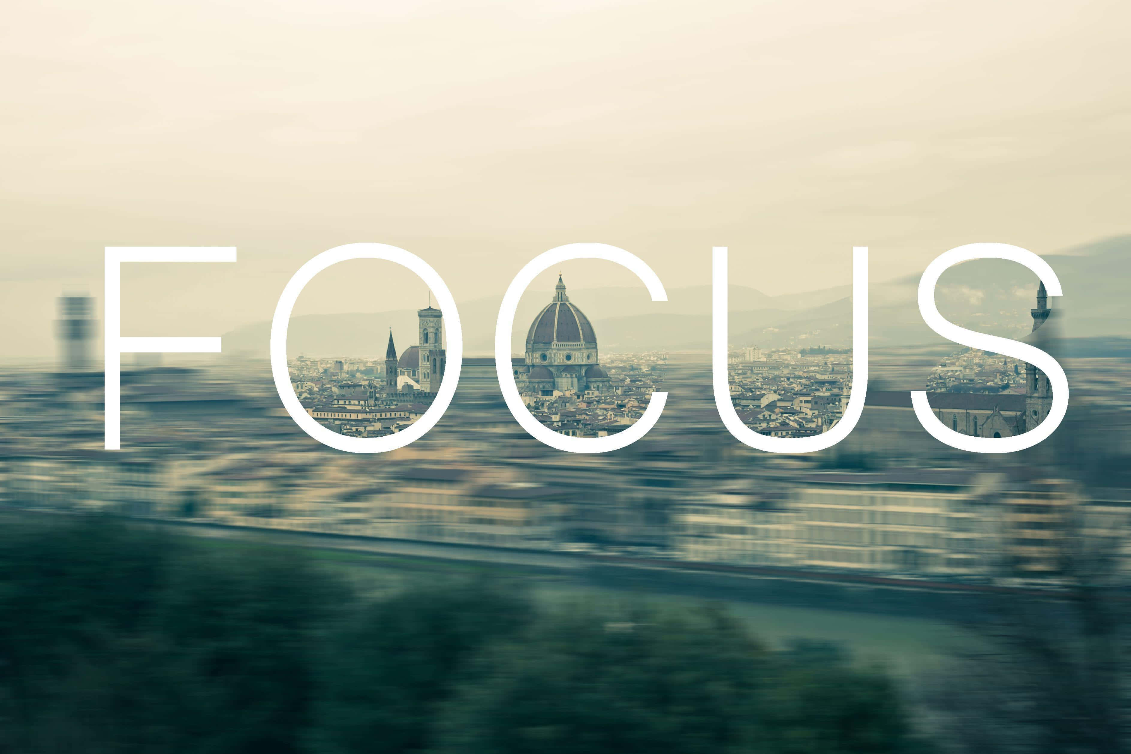 Focus 桌布 壁紙 — 「焦點」一詞疊加在模糊的城市景觀上，佛羅倫斯的圓頂透過字母可見。