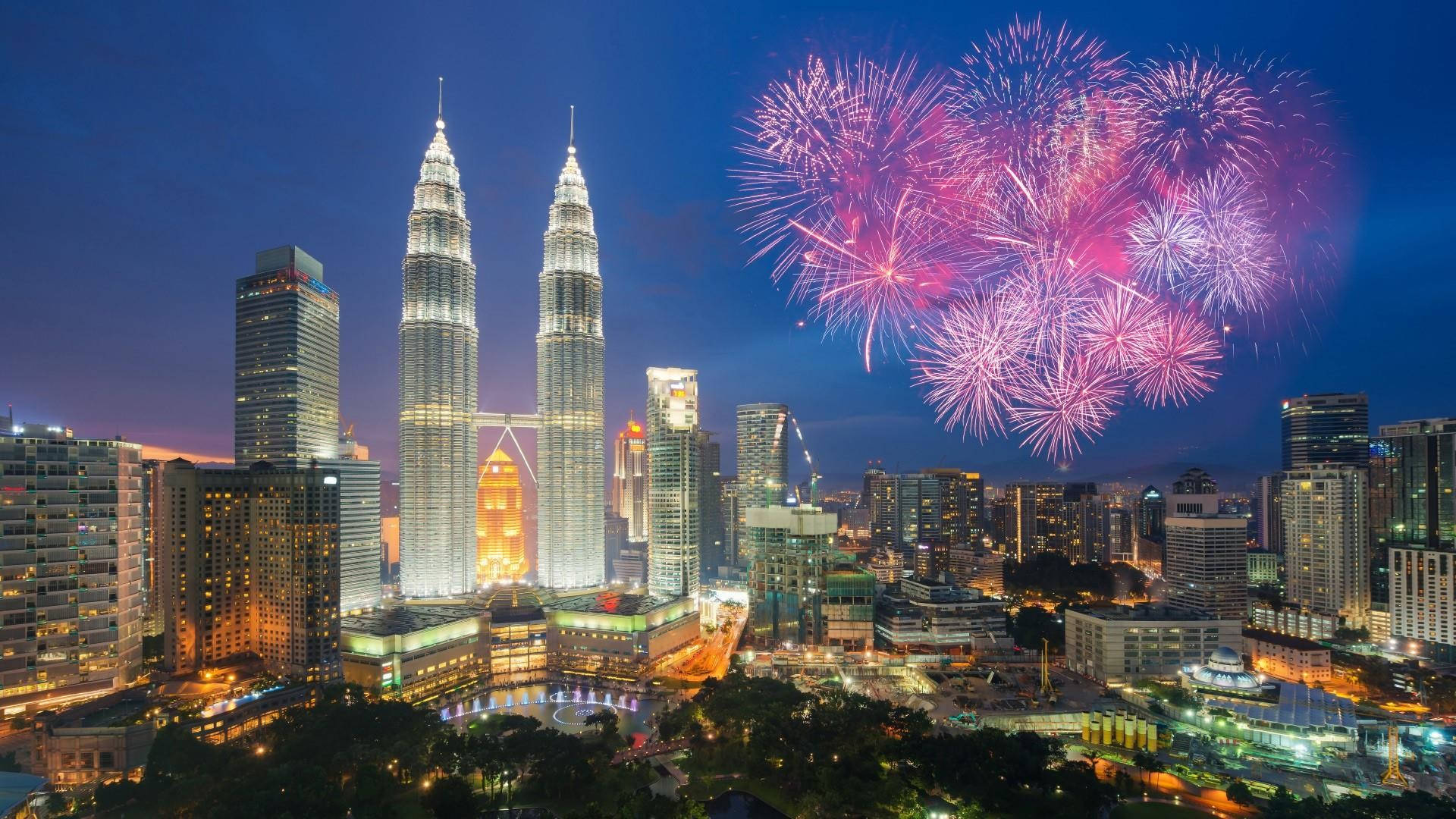 Kuala 桌布 壁紙 — 煙火在吉隆坡標誌性的雙子星塔上空綻放出鮮豔的粉紅色和紫色。