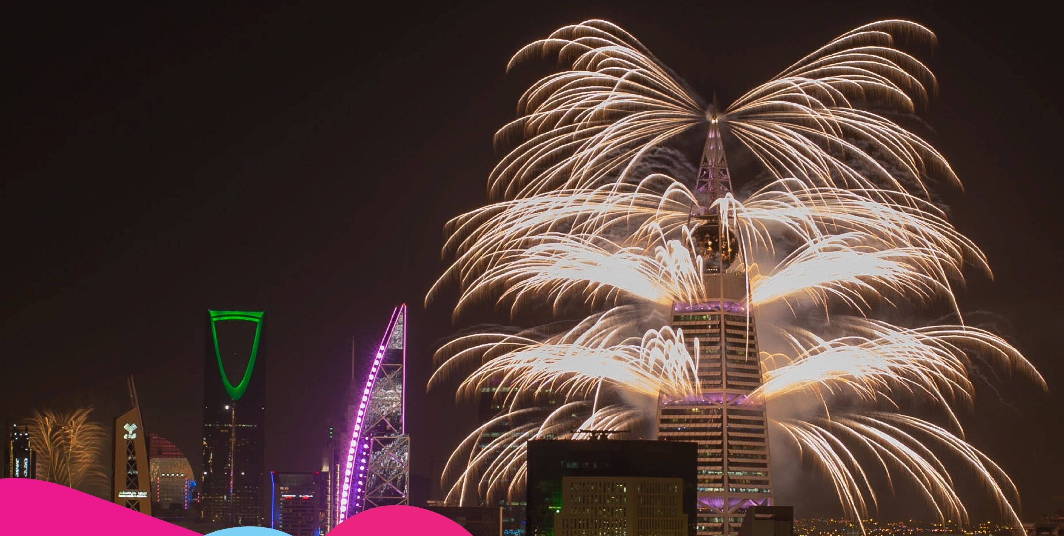 Riyadh 桌布 壁紙 — 煙火在現代城市天際線上空以金色爆發，夜晚被霓虹燈照亮。