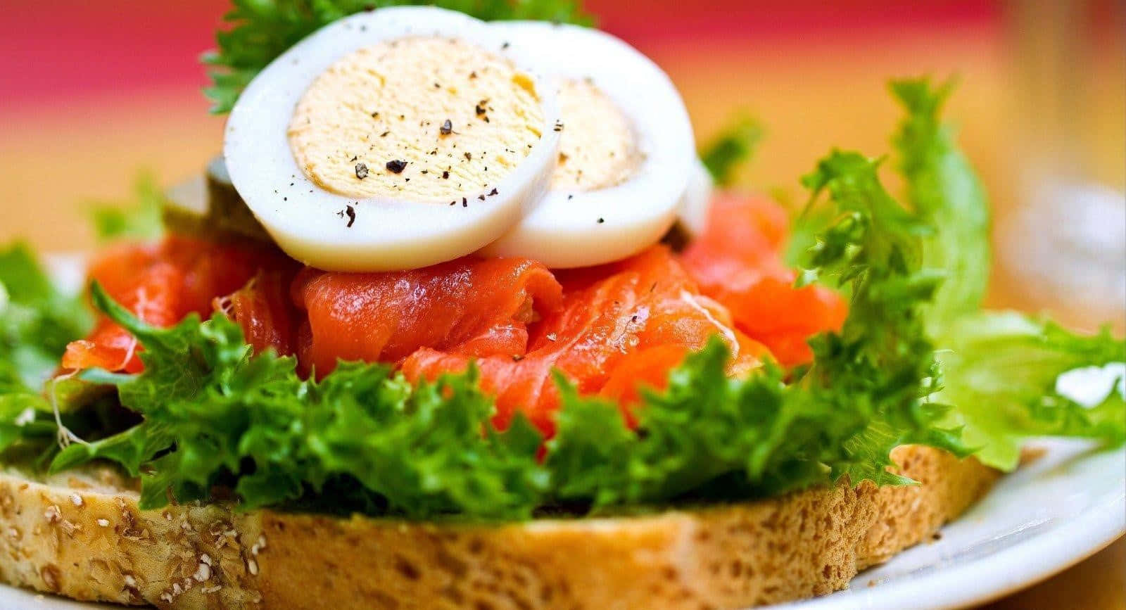 Egg 桌布 壁紙 — 煙燻鮭魚和切片水煮蛋放在脆生菜和全麥麵包上的三明治特寫。