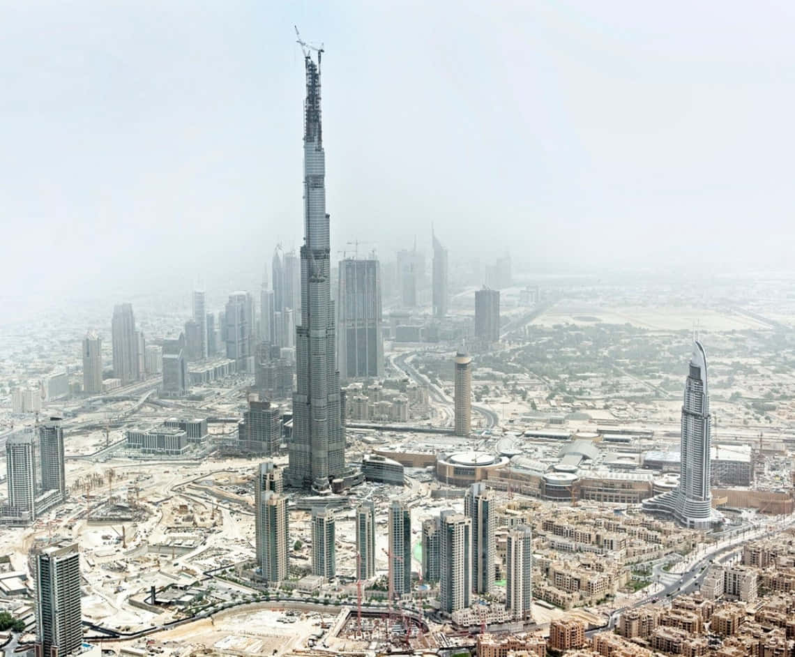 Burj Khalifa 桌布 壁紙 — 煙霞籠罩下，杜拜現代天際線上正在興建的哈里發塔的鳥瞰圖。