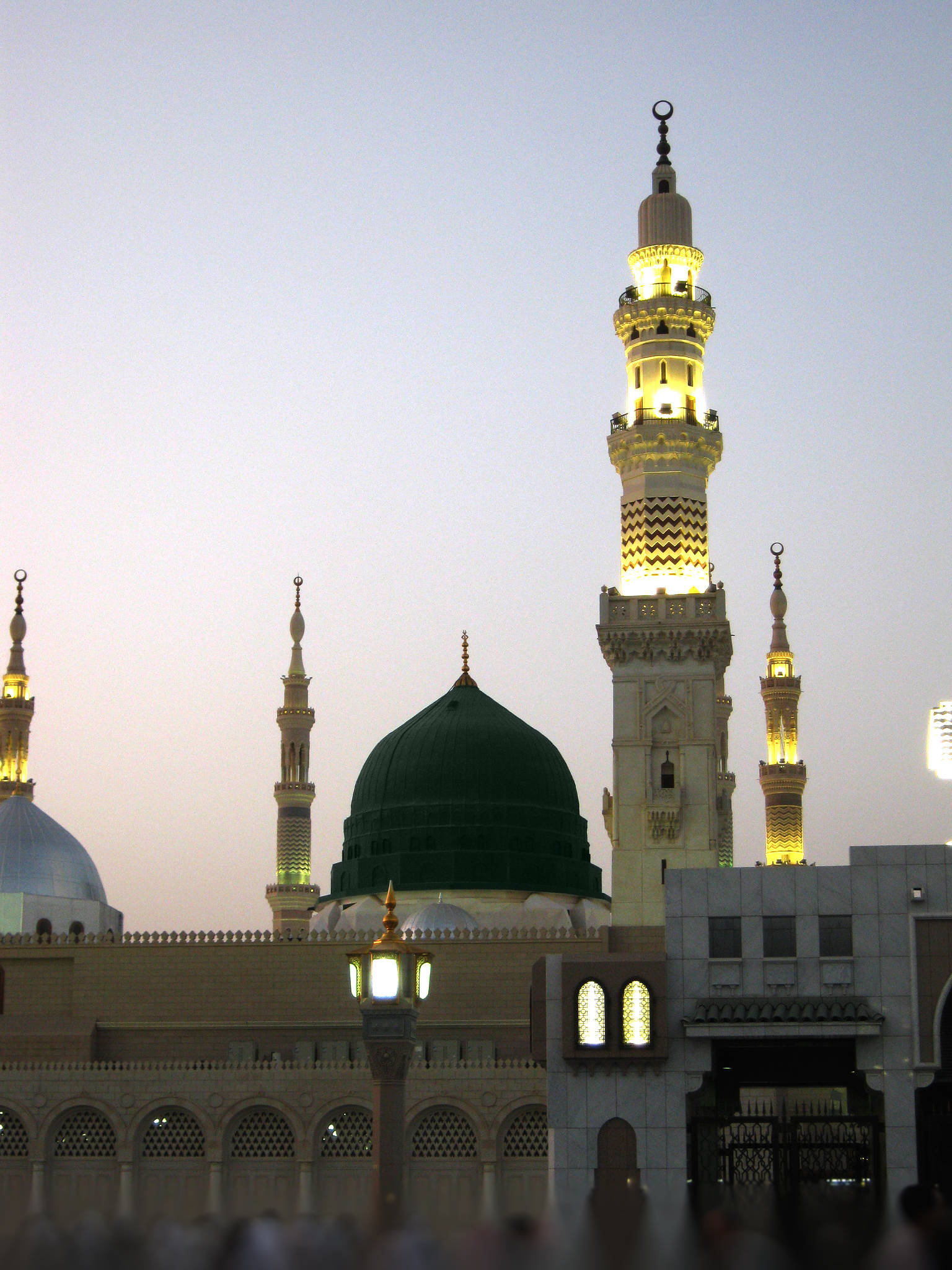 Madina Sharif 桌布 壁紙 — 照亮了的清真寺宣禮塔和綠色圓頂在柔和的暮色天空下溫暖地發光。