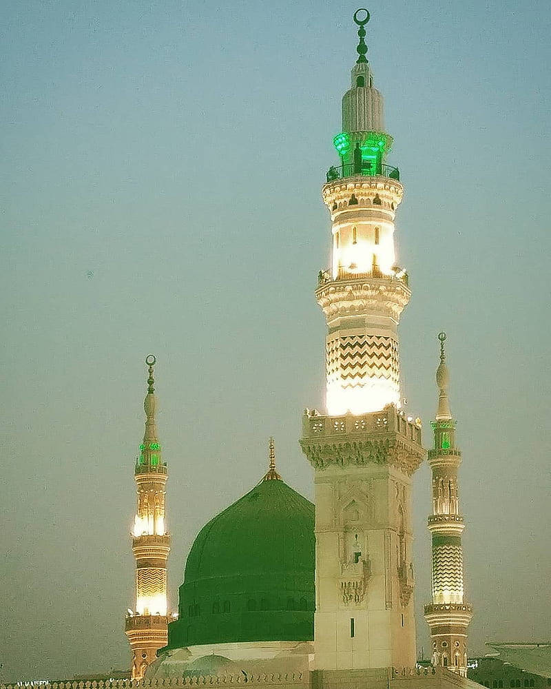 Madina 桌布 壁紙 — 照亮了的清真寺宣禮塔和綠色圓頂在淡色的黃昏天空下溫暖地發光。
