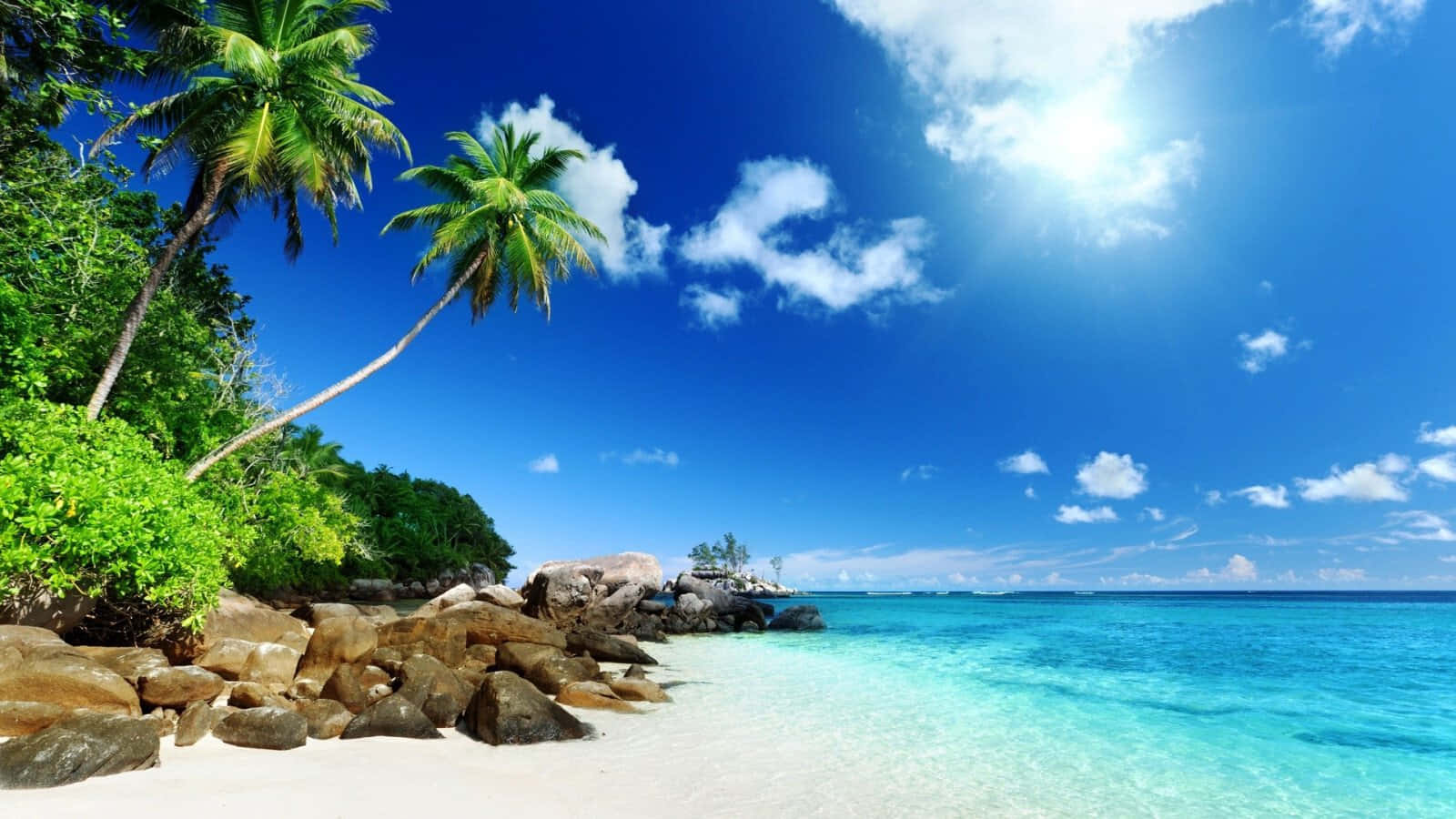 Beach Aesthetic 桌布 壁紙 — 熱帶天堂，有白色沙灘、碧綠海水和棕櫚樹，在明亮的藍天下有蓬鬆的雲朵。