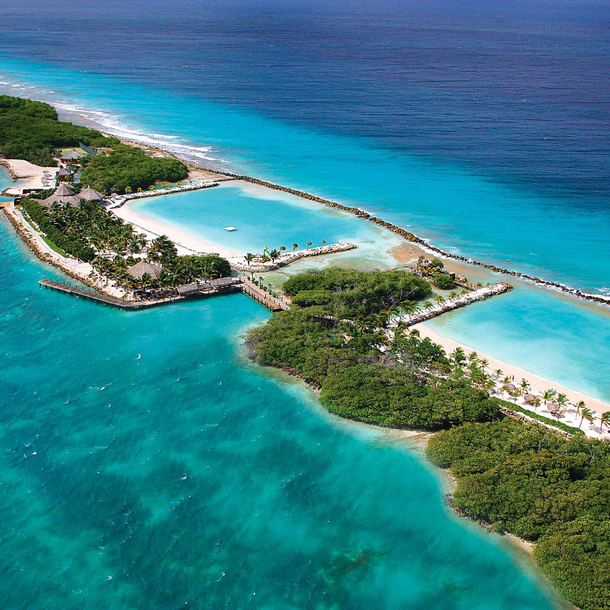 Aruba 桌布 壁紙 — 熱帶島嶼度假村的鳥瞰圖，擁有碧綠色的潟湖、白色沙灘和茂密的綠色植物，被深藍色的海洋包圍。