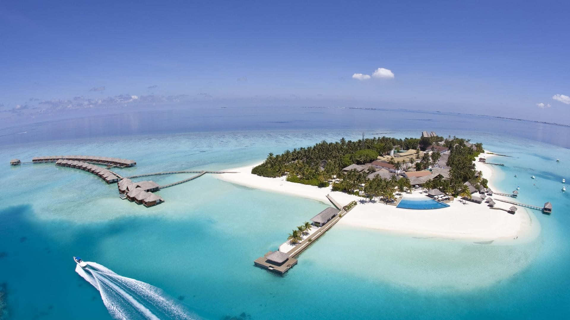 Maldives Beach 桌布 壁紙 — 熱帶島嶼度假村的鳥瞰圖，設有水上平房、碧綠色的潟湖和一艘快艇劃破水面。