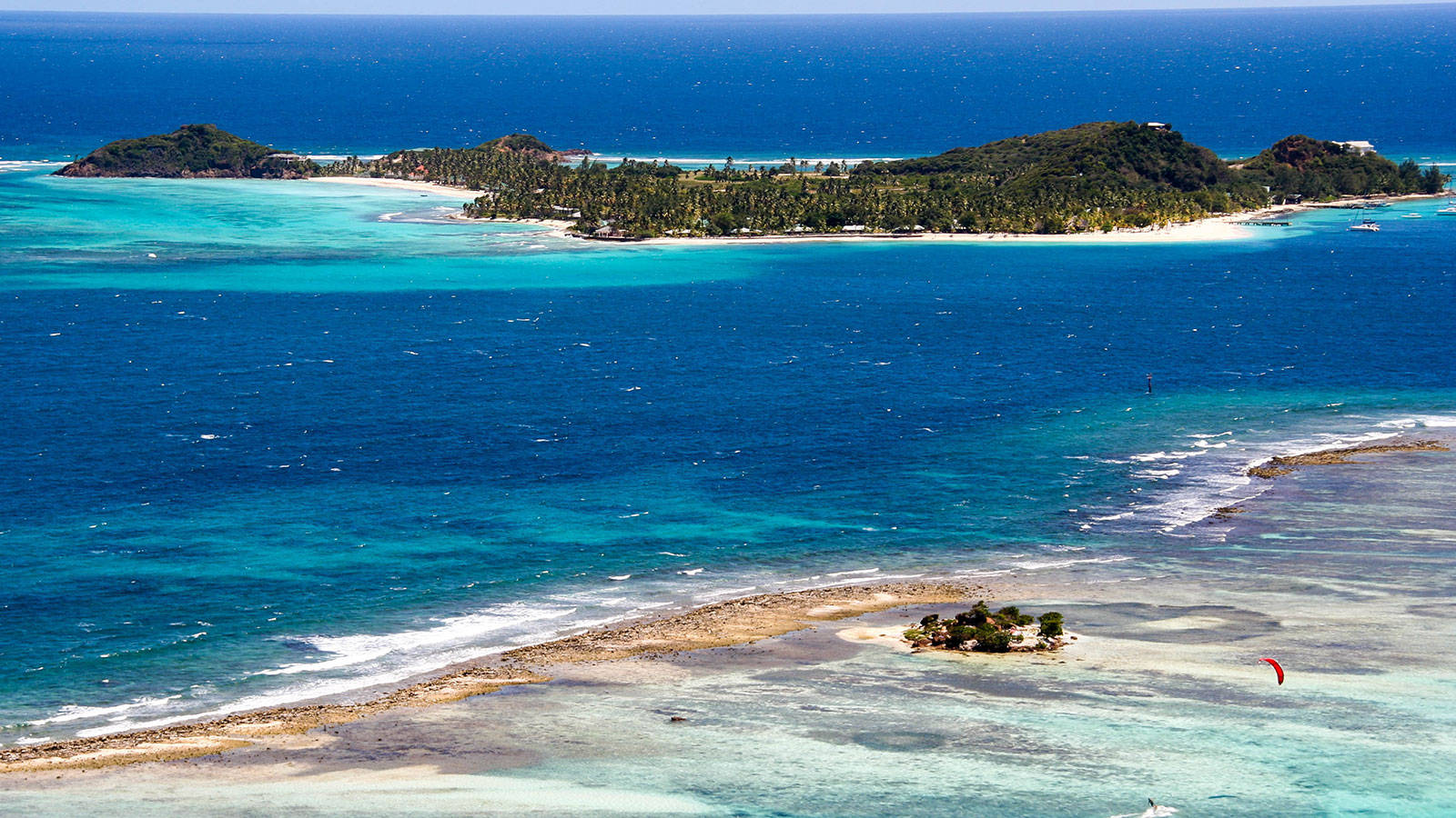 St Vincent And The Grenadines 桌布 壁紙 — 熱帶島鏈的鳥瞰圖，擁有碧綠色的潟湖、白色沙灘和茂密的綠色植物，被深藍色的海洋環繞。
