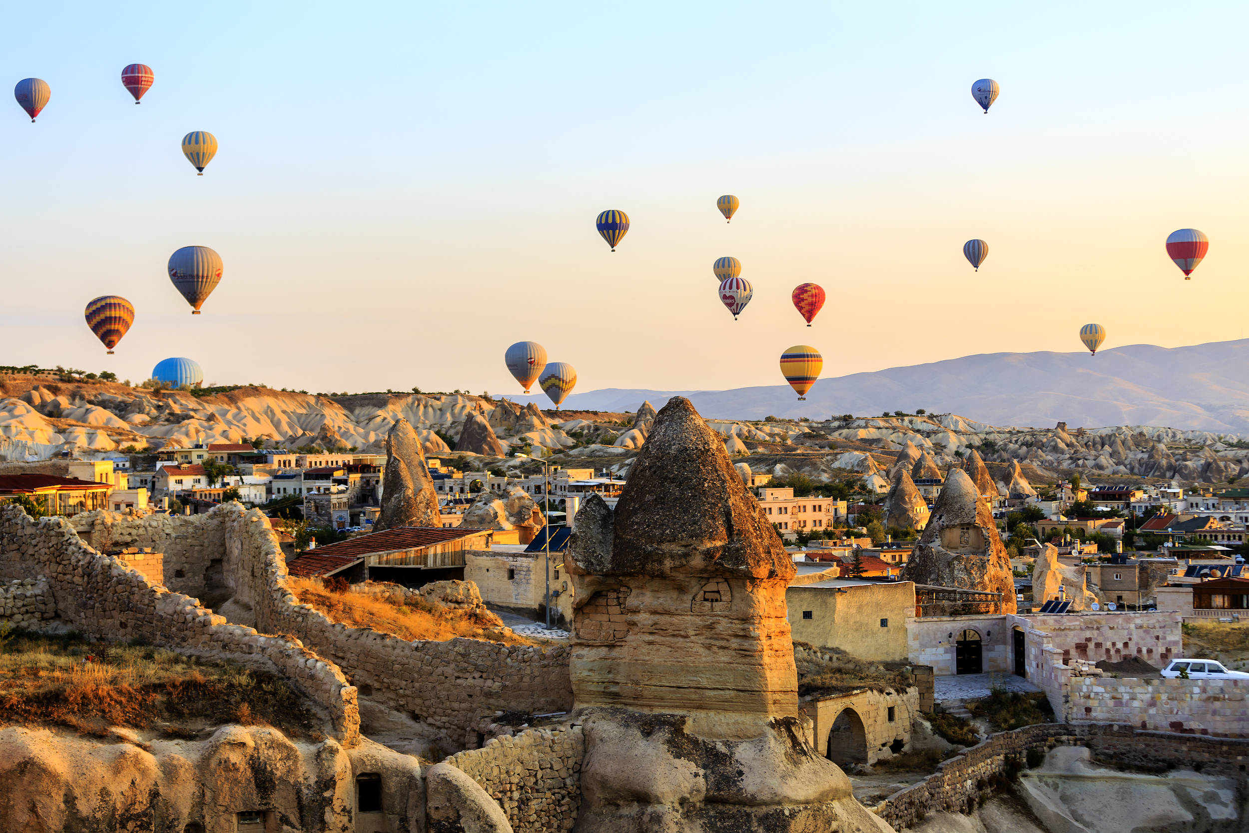 Cappadocia 桌布 壁紙 — 熱氣球在卡帕多奇亞的童話煙囪上空飄浮，金色夕陽為石村灑下溫暖的光芒。