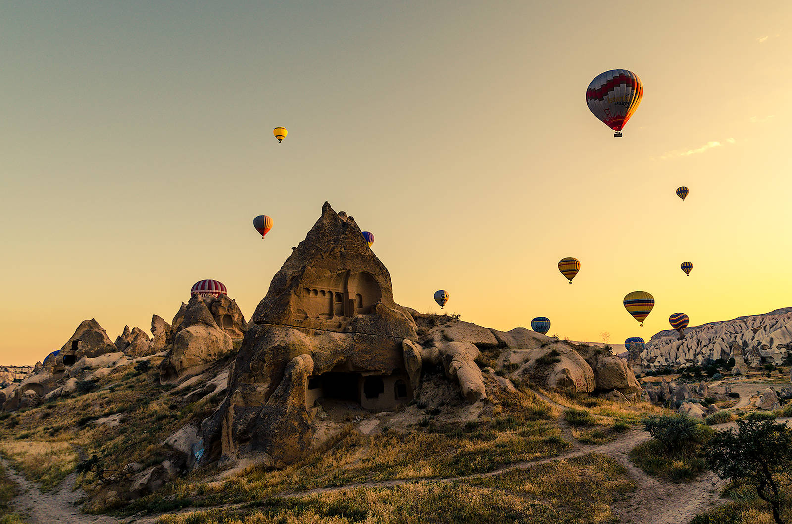 Cappadocia 桌布 壁紙 — 熱氣球在卡帕多奇亞金色日出時飄過古老岩層。