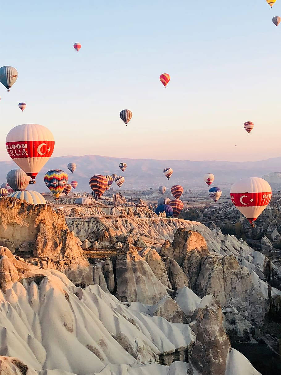 Hot Air Balloon 桌布 壁紙 — 熱氣球在土耳其卡帕多奇亞日出時飄過超現實的岩石 formations。