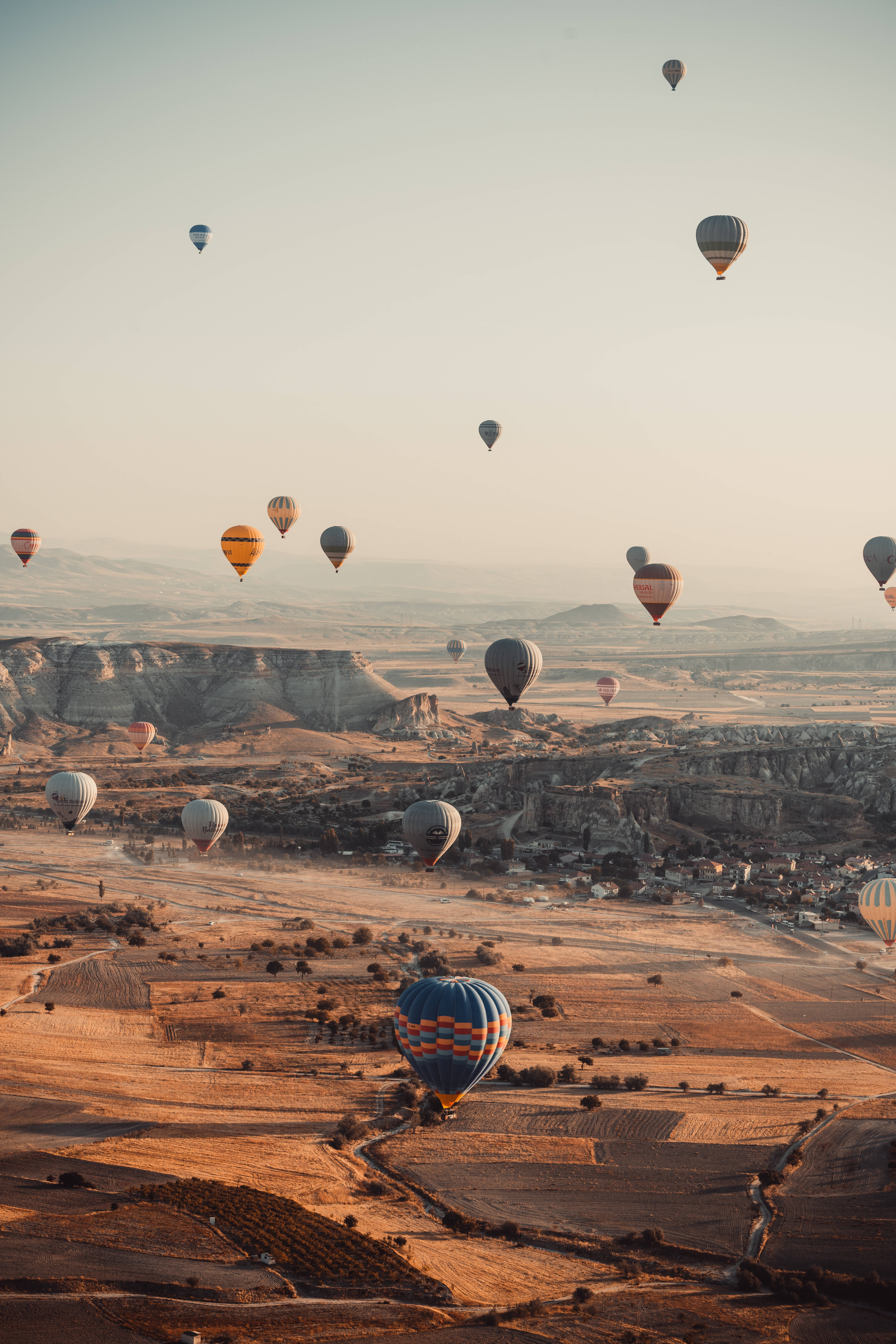 Cappadocia 桌布 壁紙 — 熱氣球在日出時分飄過金色峽谷景觀，在崎嶇地形上投下長長的陰影。