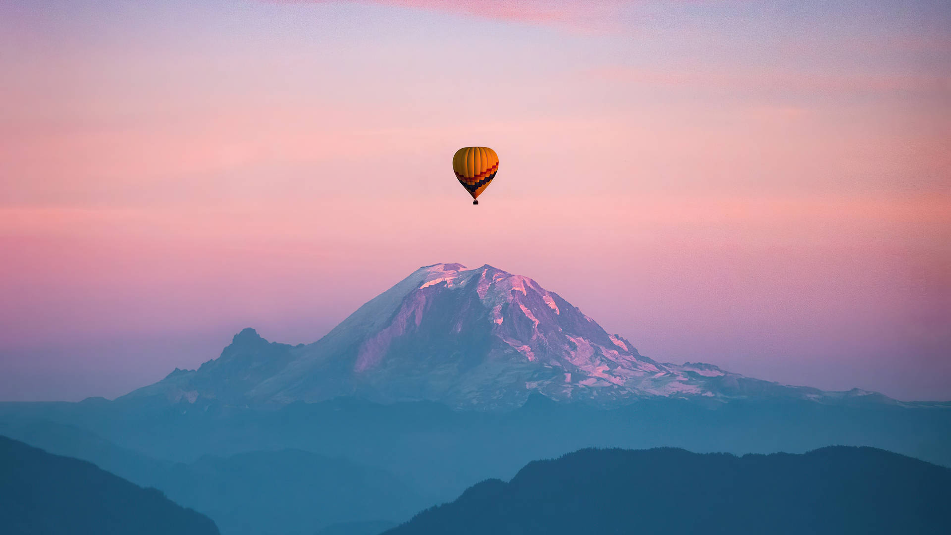 Hot Air Balloon 桌布 壁紙 — 熱氣球在柔和的粉紅色和紫色暮色天空下，寧靜地漂浮在積雪的山峰之上。