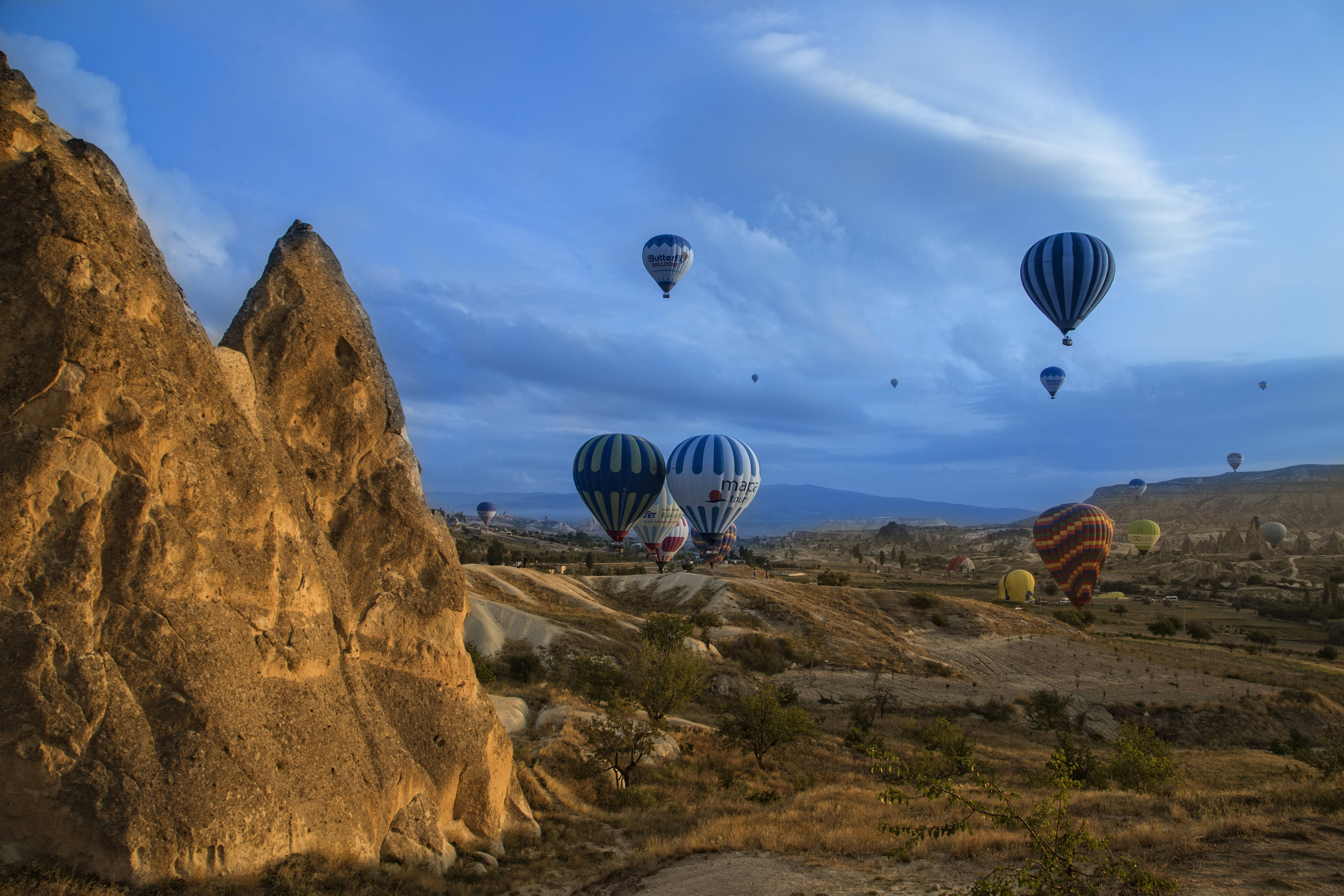 Cappadocia 桌布 壁紙 — 熱氣球在柔和的藍色暮色天空下，飄過卡帕多奇亞崎嶇的岩石地貌。