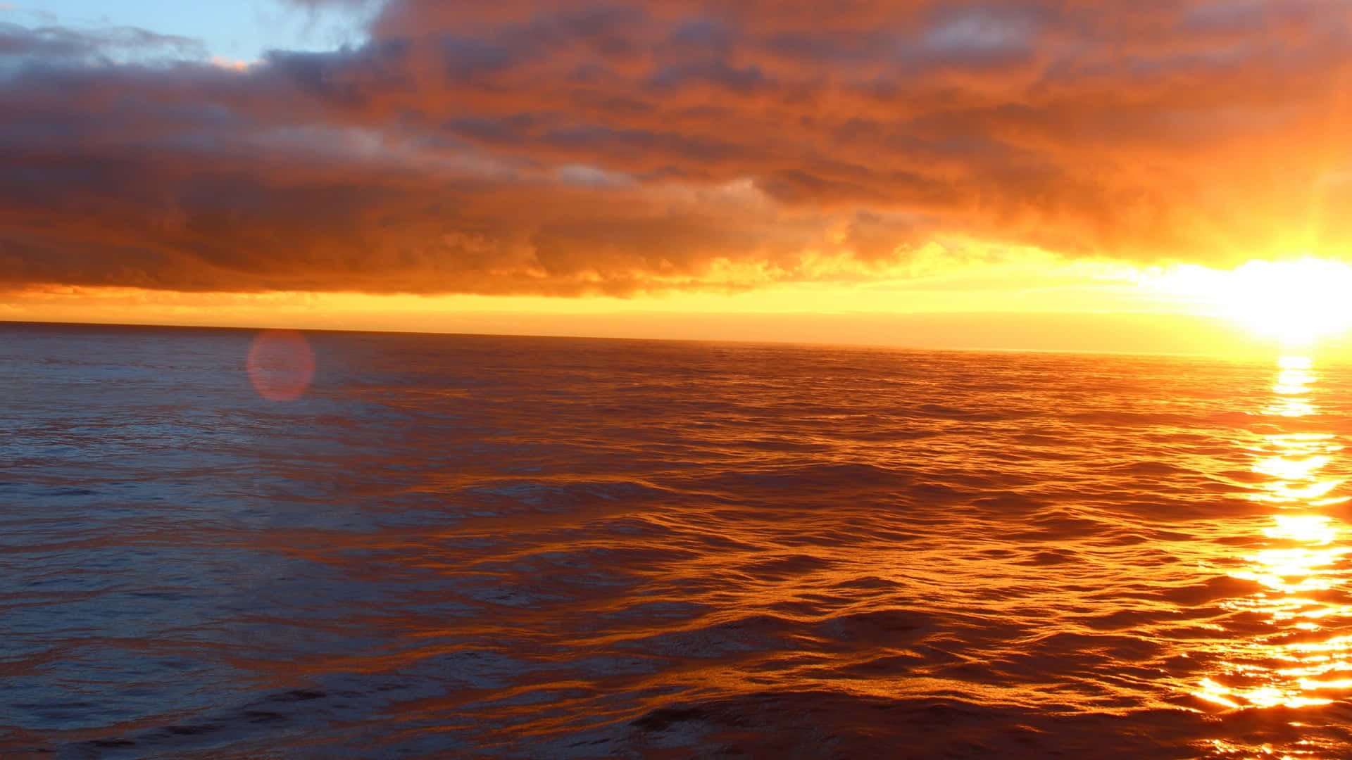 Pretty Ocean 桌布 壁紙 — 熾熱的夕陽將海洋染成閃耀的橙色和金色，太陽沉入地平線下。