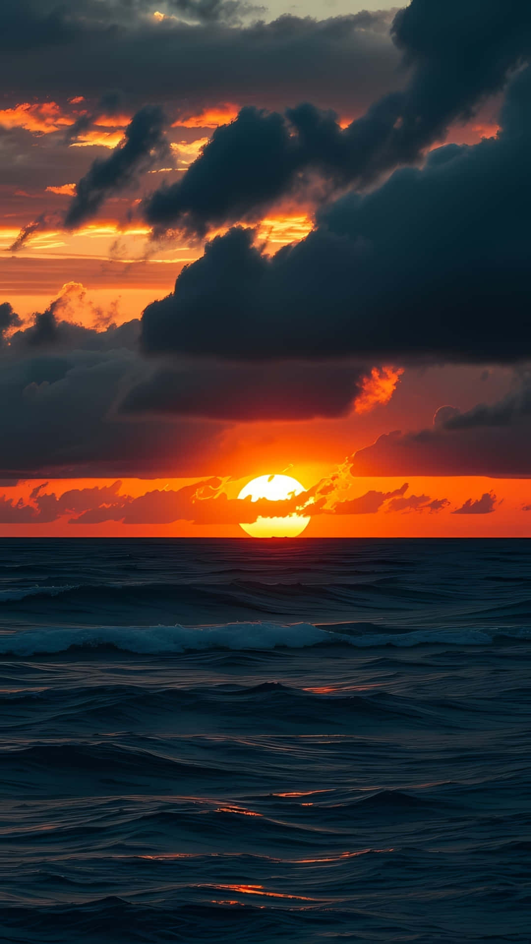 Dramatic Sunset Over Dark Ocean Waves 壁紙 — 熾熱的日落，發光的太陽部分被烏雲遮擋，在波濤洶湧的海洋上投射出鮮豔的橙色和紅色色調。