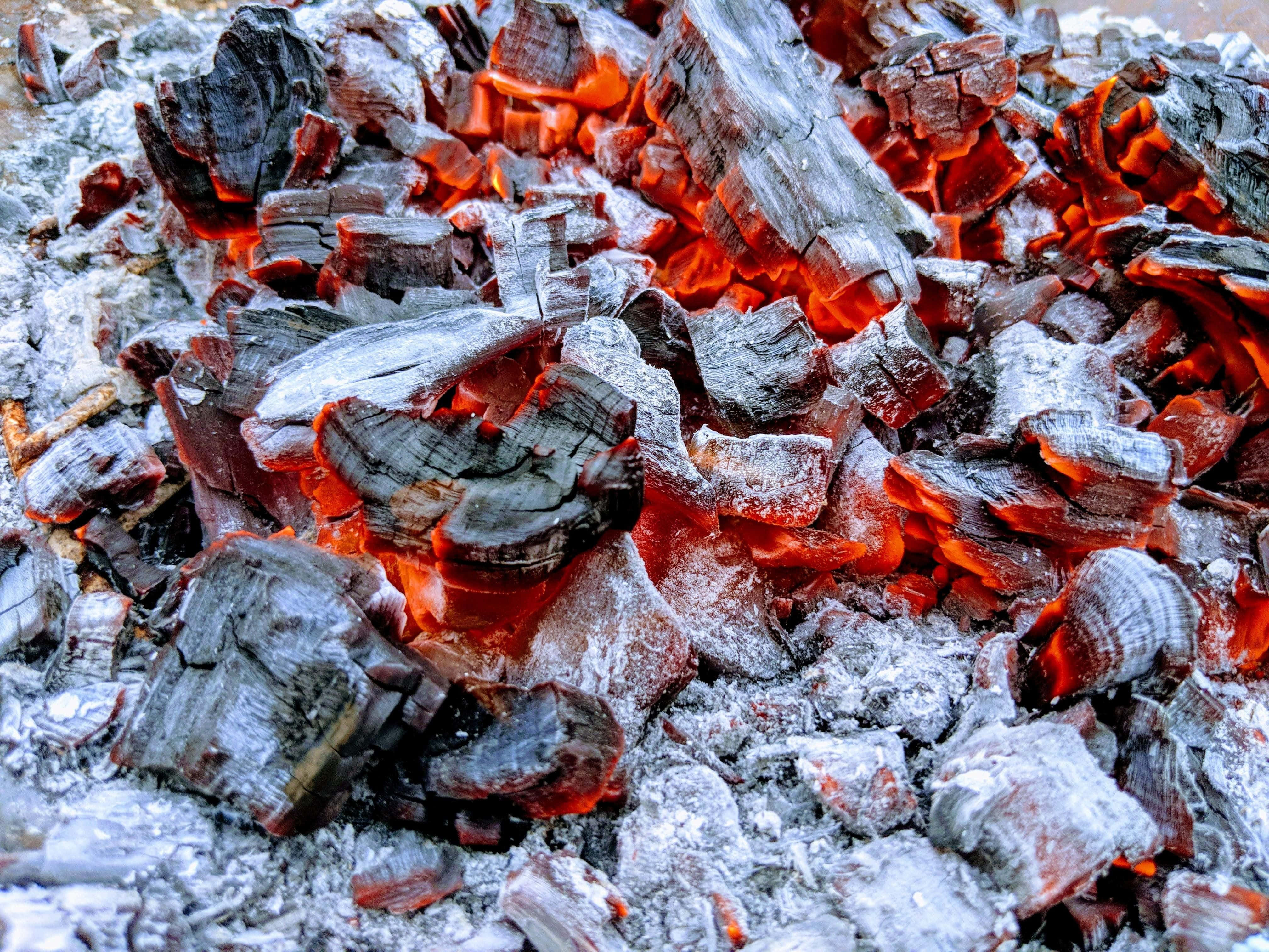Charcoal 桌布 壁紙 — 燃燒木材中發光的餘燼和灰燼的特寫，帶有鮮豔的橙紅色熱量從裂開的木炭中散發出來。
