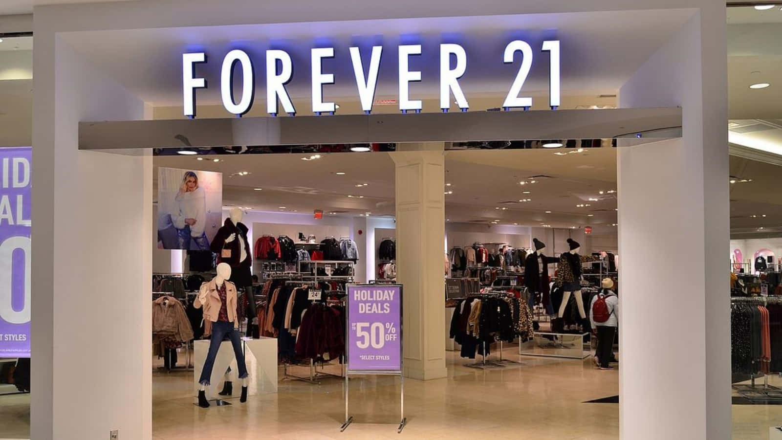 永遠21 桌布 壁紙 — 燈光明亮的Forever 21商店入口，展示著穿著時尚服裝的人體模型和一個顯眼的50%假期優惠標誌。