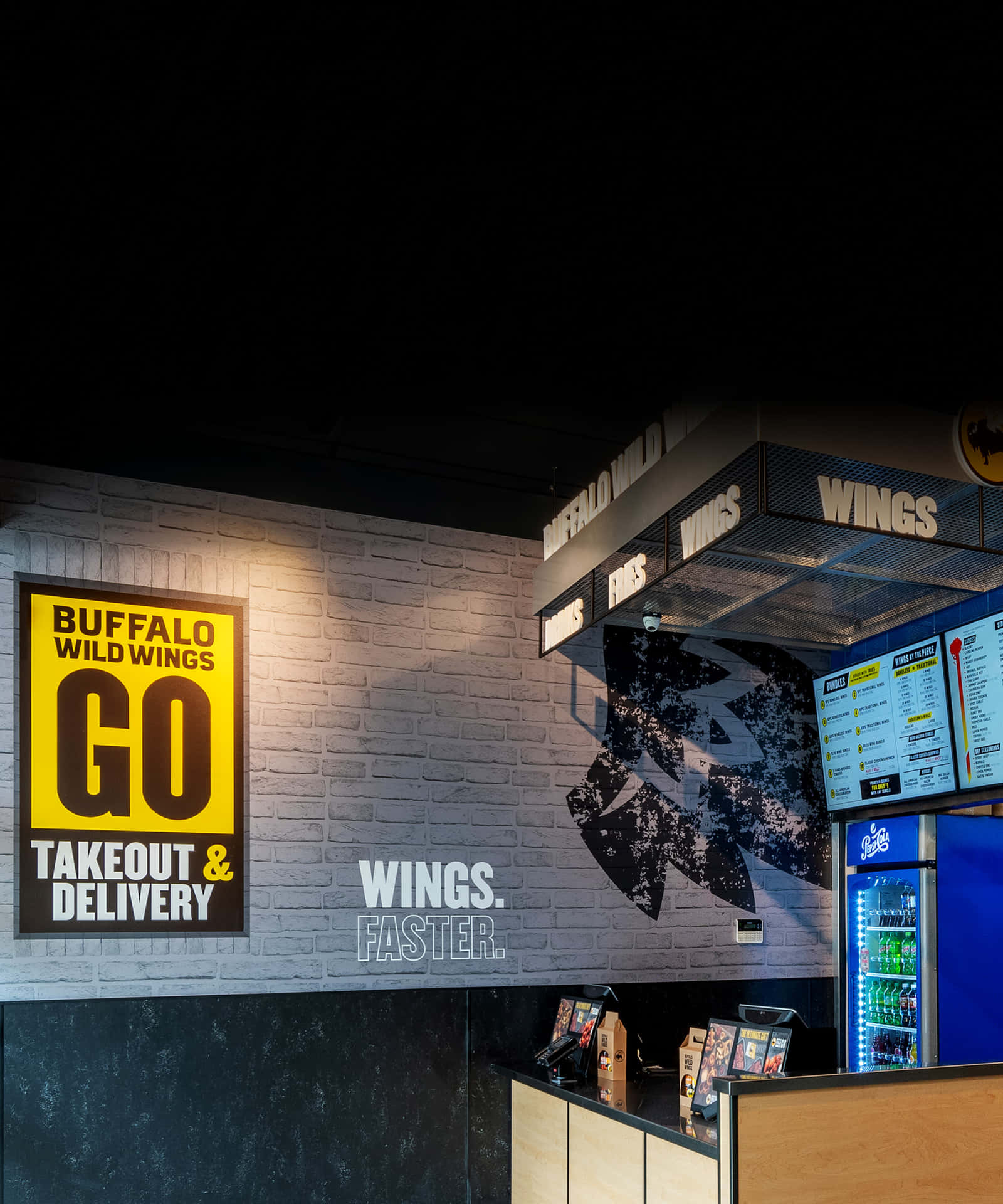 Buffalo Wild Wings餐廳內部，設有霓虹燈招牌和飲料冷卻器。