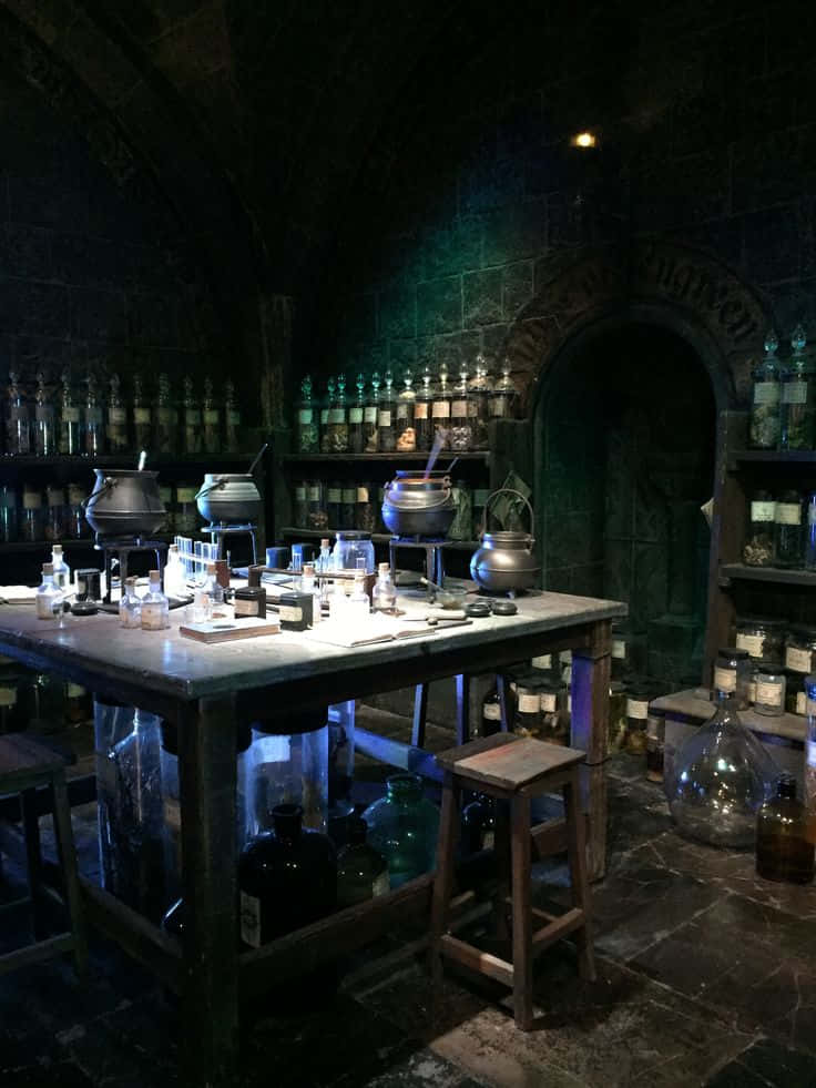 The Hogwarts Potions Class 桌布 壁紙 — 燈光昏暗的中世紀風格藥水實驗室，石牆、玻璃瓶架和木桌上的大鍋。