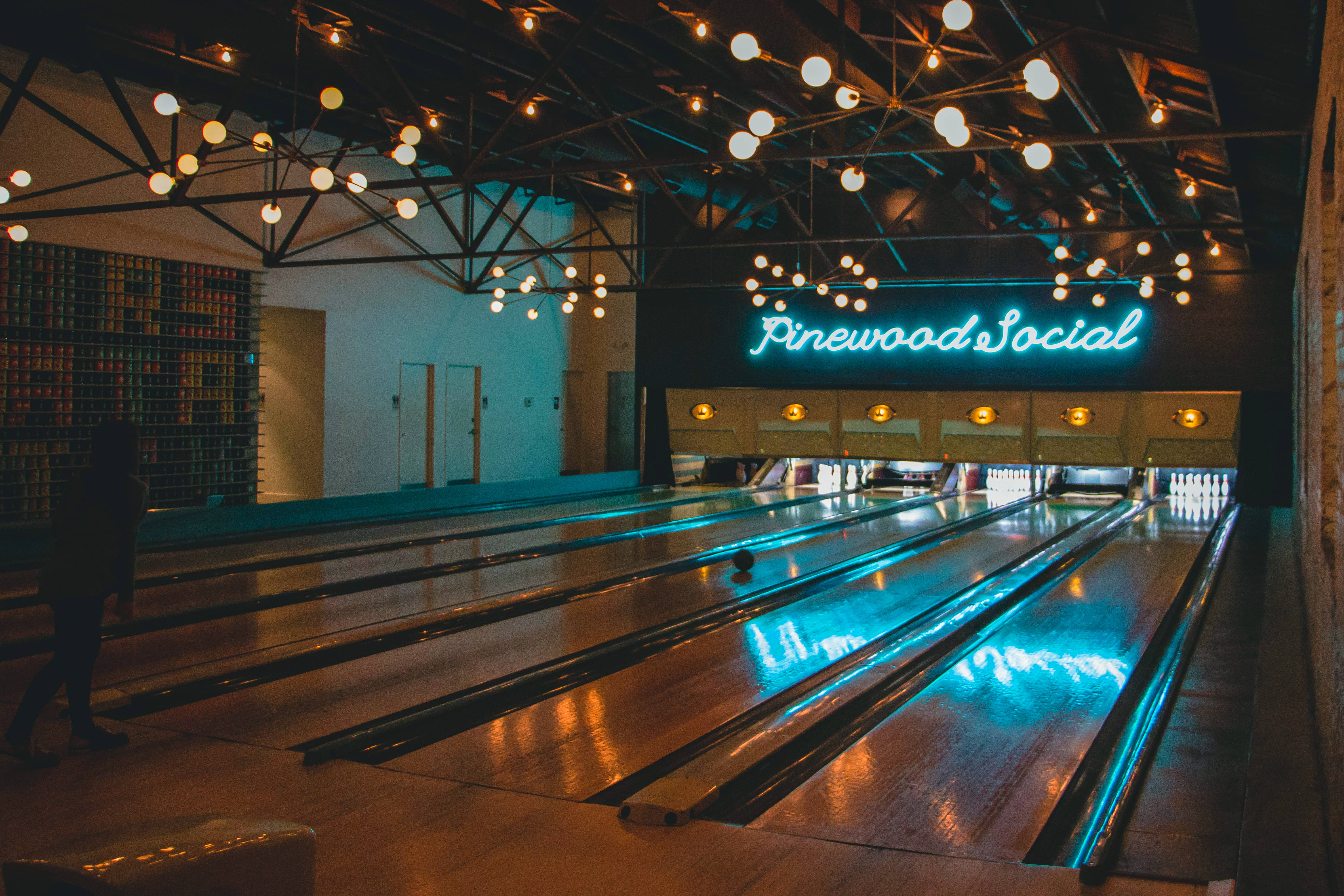 Bowling 桌布 壁紙 — 燈光昏暗的保齡球館，發光的霓虹燈招牌和溫暖的串燈反射在拋光的球道上。
