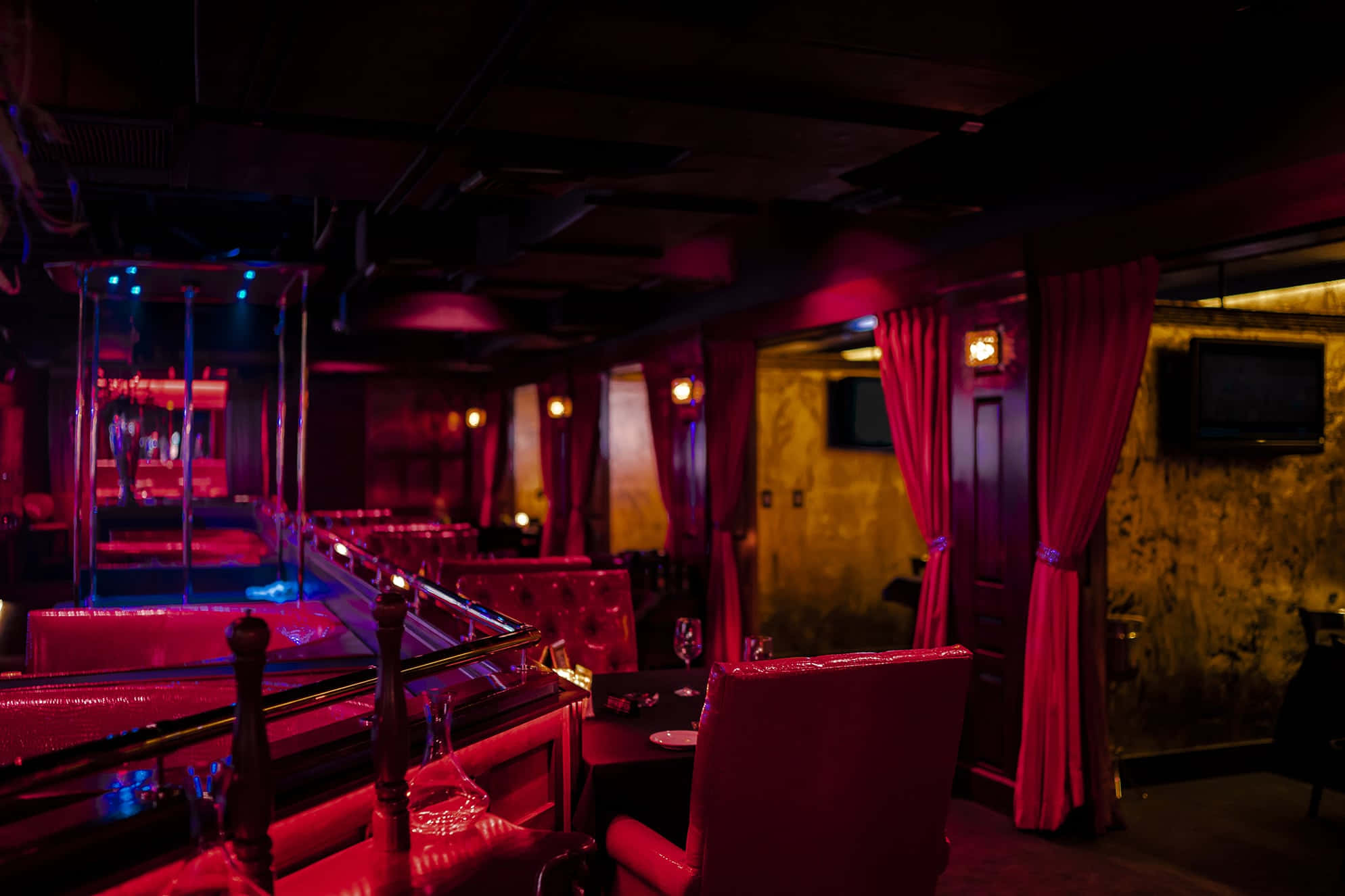 Red Room 桌布 壁紙 — 燈光昏暗的夜總會，紅色天鵝絨窗簾和豪華座椅沐浴在憂鬱的紅色和藍色霓虹燈中。