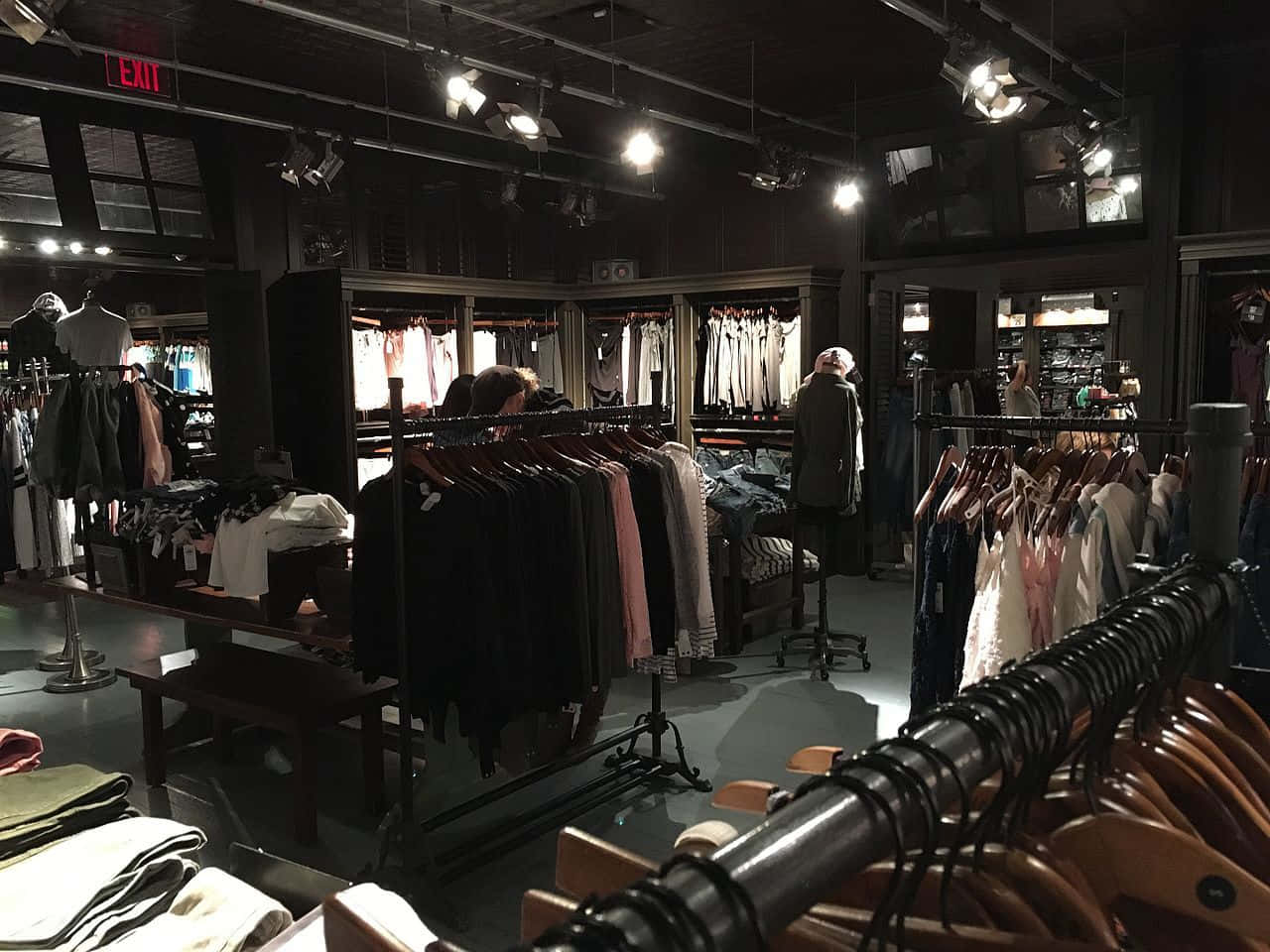 hollister 桌布 壁紙 — 燈光昏暗的精品店，聚光燈下的衣架和模特兒投射出戲劇性的陰影。