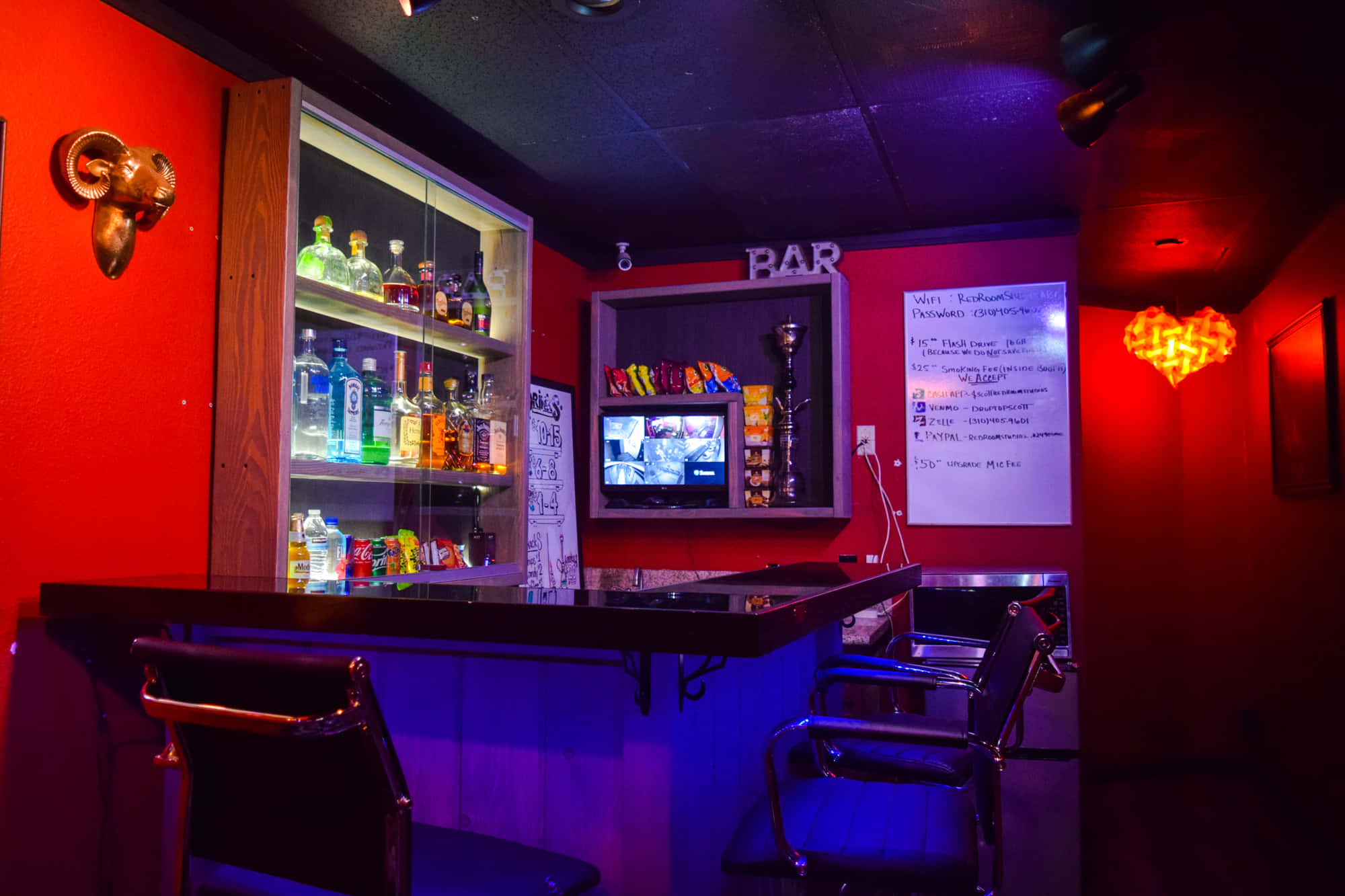 Red Room 桌布 壁紙 — 燈光昏暗的酒吧，紅色牆壁和藍色霓虹燈光，展示玻璃架後面的酒瓶和吧檯前的金屬凳子。