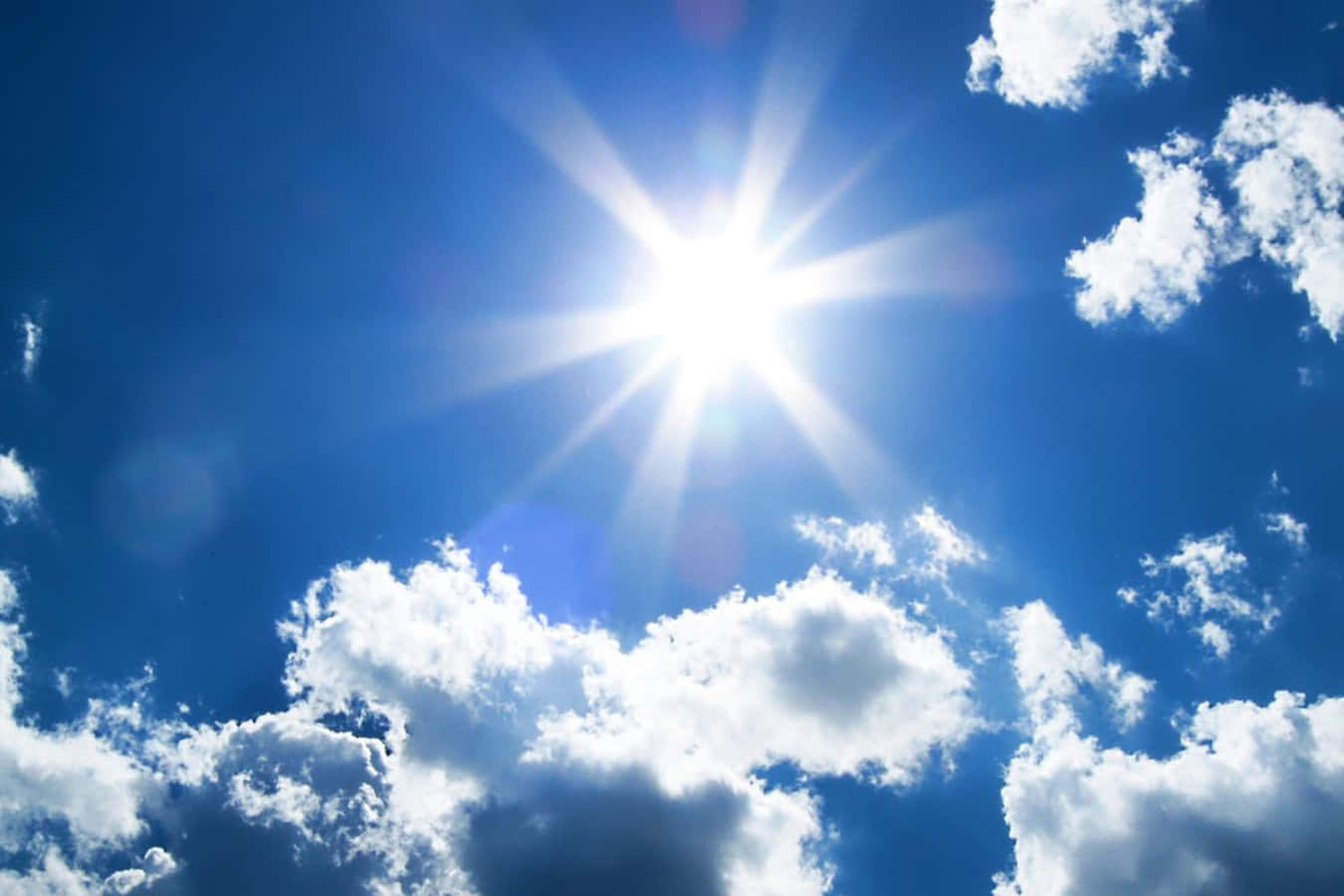 Bright 桌布 壁紙 — 燦爛的太陽在佈滿蓬鬆白雲的鮮豔藍天上散發出強烈的光芒。