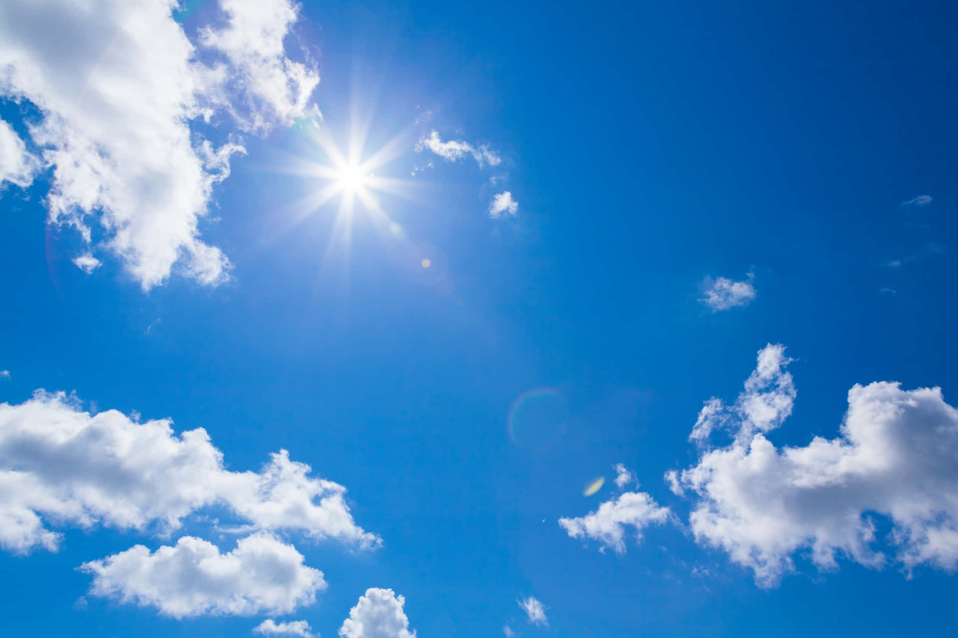 Blue Skies 桌布 壁紙 — 燦爛的太陽在蔚藍的天空中透過蓬鬆的白雲散發出明亮的光芒。