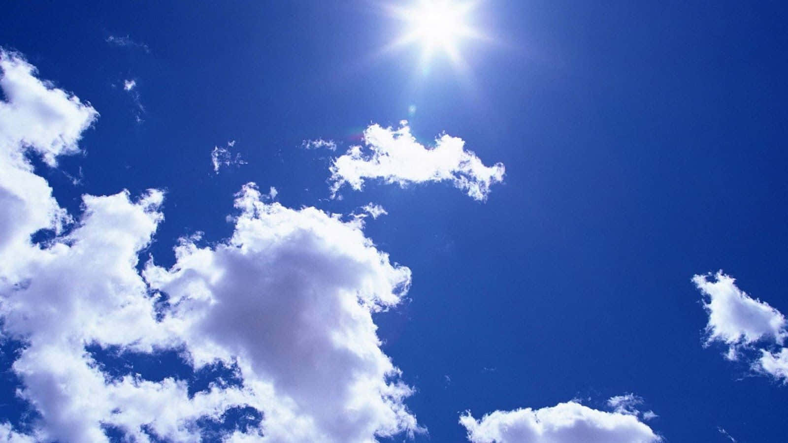 自然 桌布 壁紙 — 燦爛的太陽在鮮豔的藍天中透過蓬鬆的白雲散發出明亮的光芒。