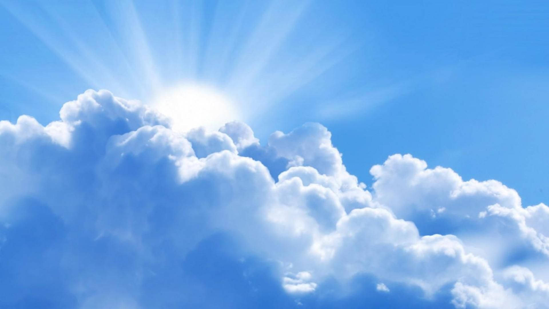 旭日東昇 桌布 壁紙 — 燦爛的太陽穿過蓬鬆的白雲，在充滿活力的藍天中投射出戲劇性的光線。