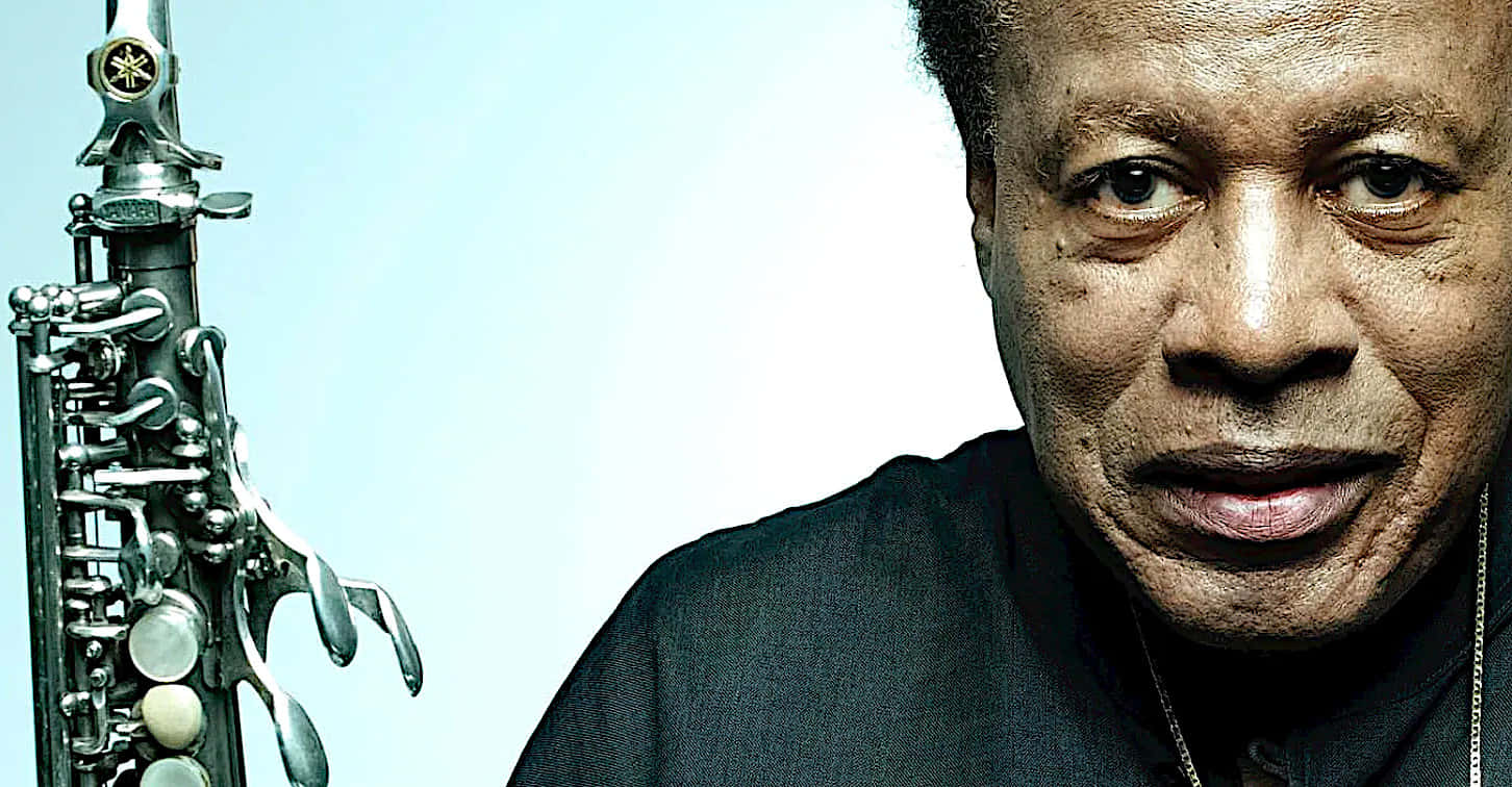 Wayne Shorter 桌布 壁紙 — 爵士傳奇 Sonny Rollins 手持薩克斯風的特寫肖像，背景為柔和藍色漸層。