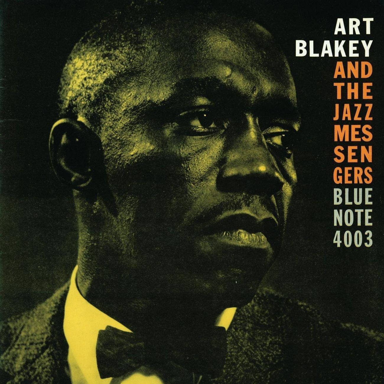 Album Cover 桌布 壁紙 — 爵士鼓手 Art Blakey 的近距離肖像，身穿深色西裝和領結，在戲劇性的黃綠色燈光下。