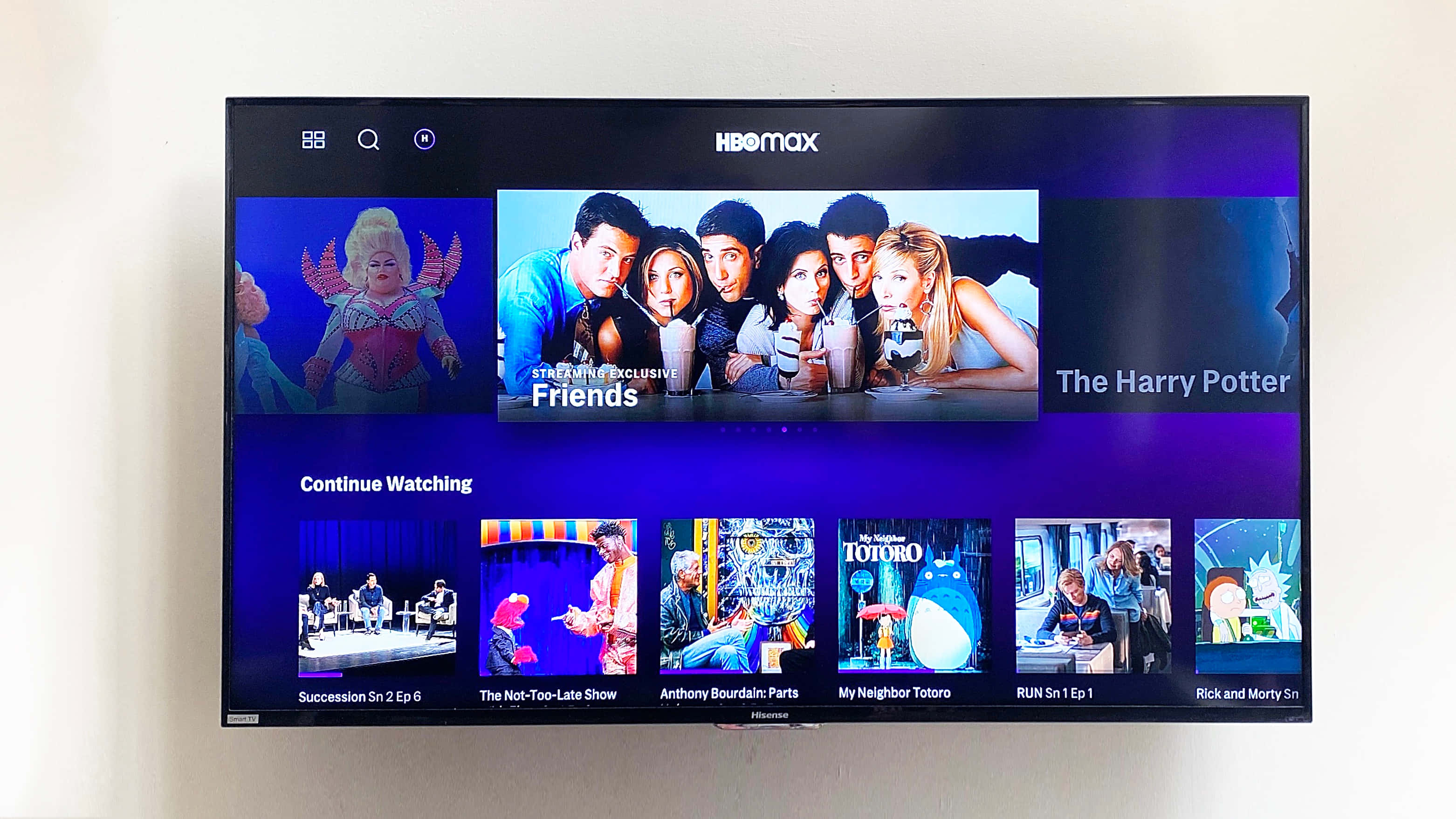 HBO 桌布 壁紙 — 牆上電視顯示HBO Max串流介面，帶有Friends和Harry Potter等節目縮圖，背景為紫色漸變。
