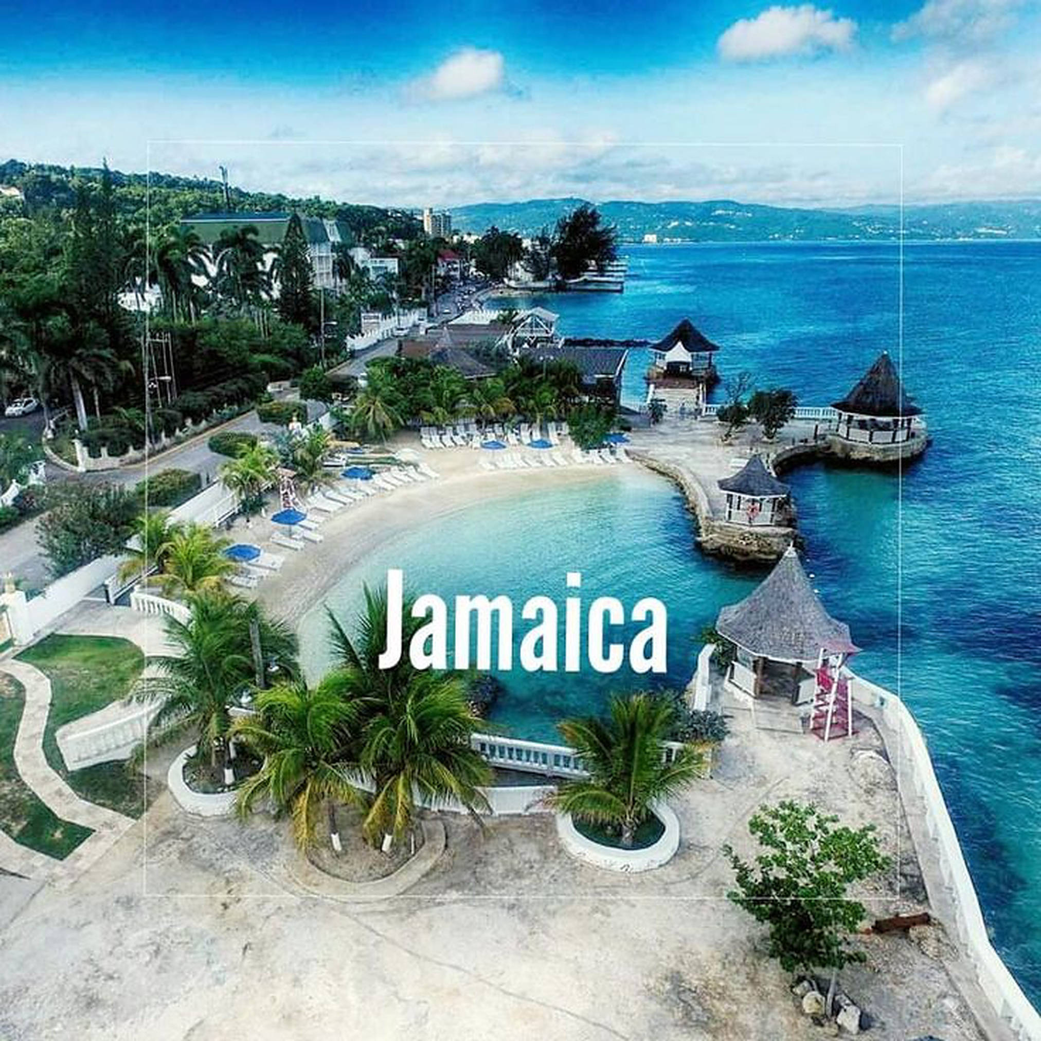 Jamaica Beach 桌布 壁紙 — 牙買加熱帶海灘度假村的鳥瞰圖，有碧綠的海水、棕櫚樹和茅草屋頂的小屋，在明亮的藍天下。