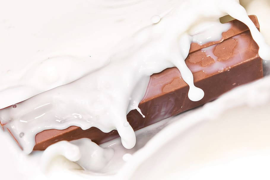 Chocolate 桌布 壁紙 — 牛奶巧克力棒部分浸在奶油白牛奶中的特寫，表面有水滴流下。