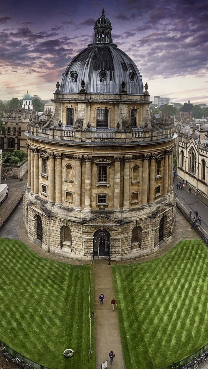 England 桌布 壁紙 — 牛津拉德克利夫相機室在黃昏時的鳥瞰圖，下方有戲劇性的紫色雲彩和修剪整齊的草坪。