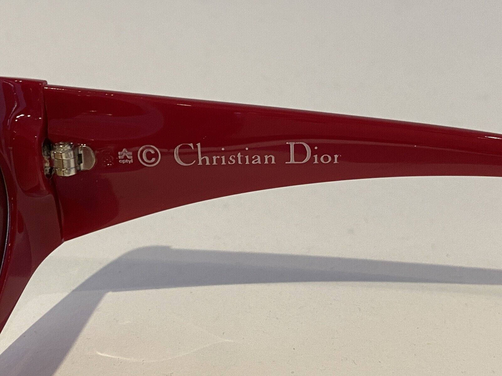 紅色Christian Dior太陽眼鏡臂，帶銀色標誌，置於白色表面。 — Dior 動態 壁紙