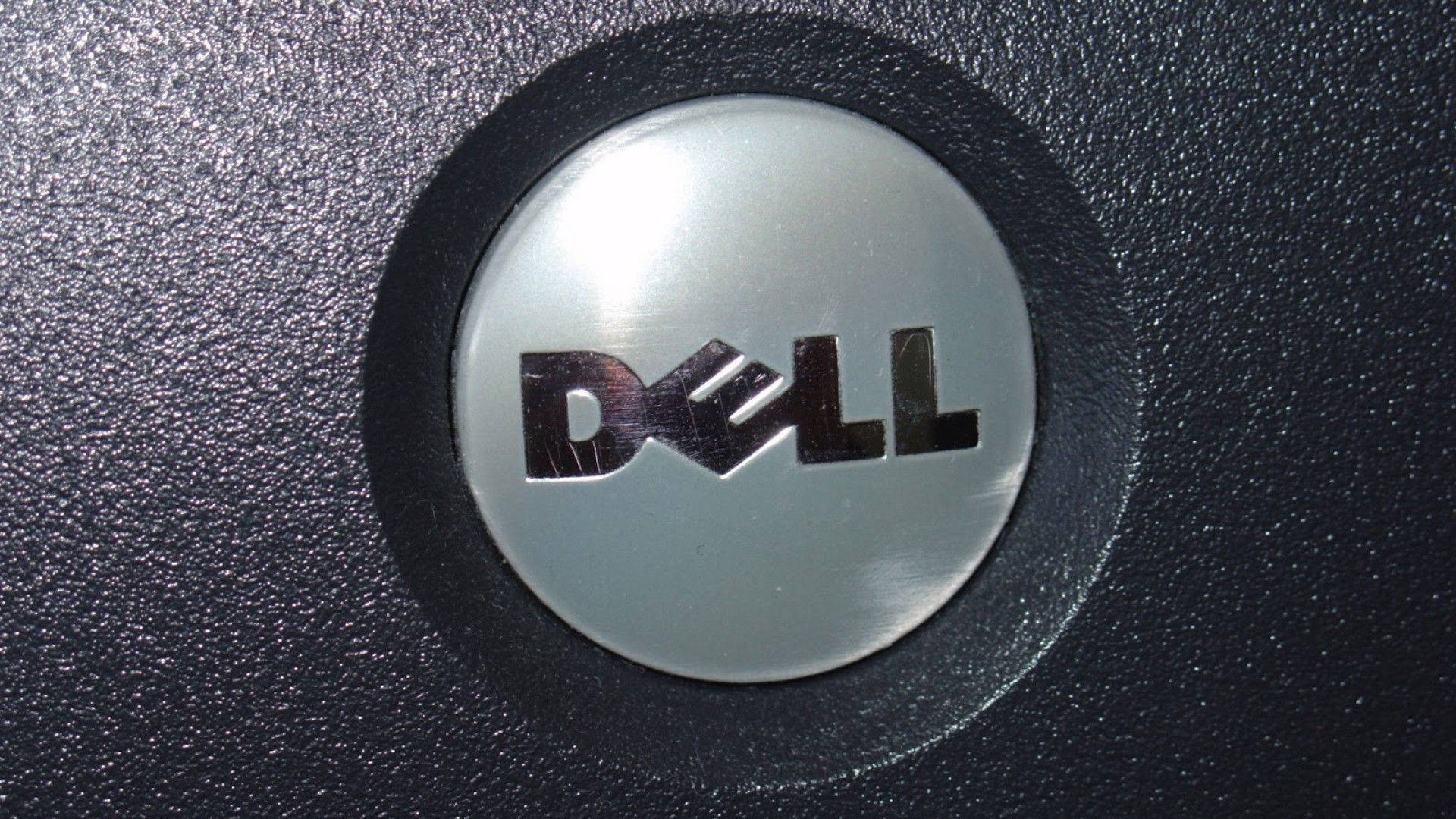 Dell 桌布 壁紙 — 特寫：拉絲金屬Dell標誌嵌入紋理黑色塑料中。