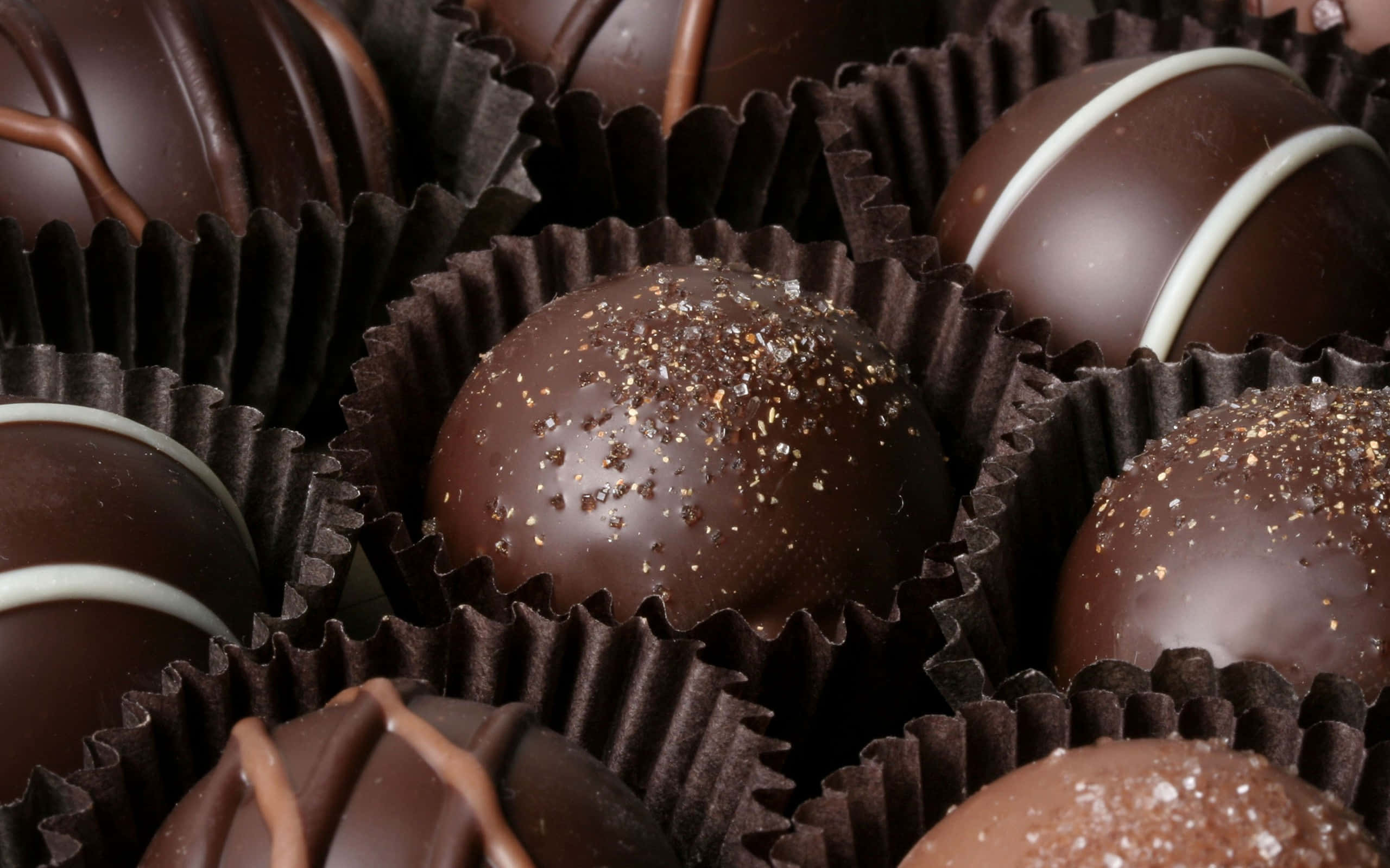 Chocolate 桌布 壁紙 — 特寫：深色巧克力松露在棕色紙杯中，表面有白色和金色淋醬和裝飾，光澤亮麗。