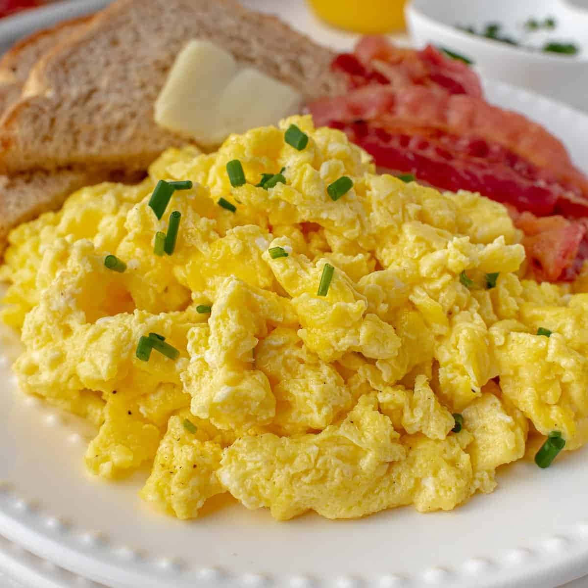 Scrambled Egg 桌布 壁紙 — 特寫：蓬鬆黃色炒蛋，上面撒上綠色細香蔥，旁邊是脆培根和奶油吐司。