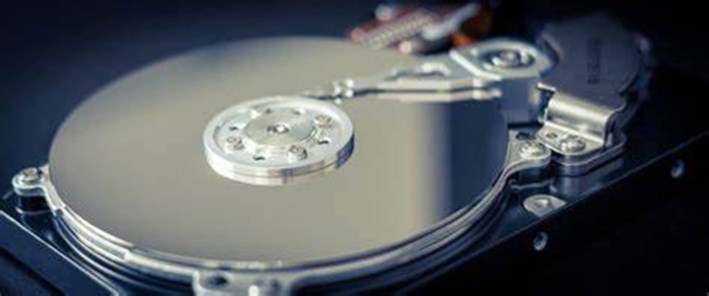 Hard Drive 桌布 壁紙 — 特寫：閃亮銀色硬碟碟片，讀寫頭對焦，背景深色。