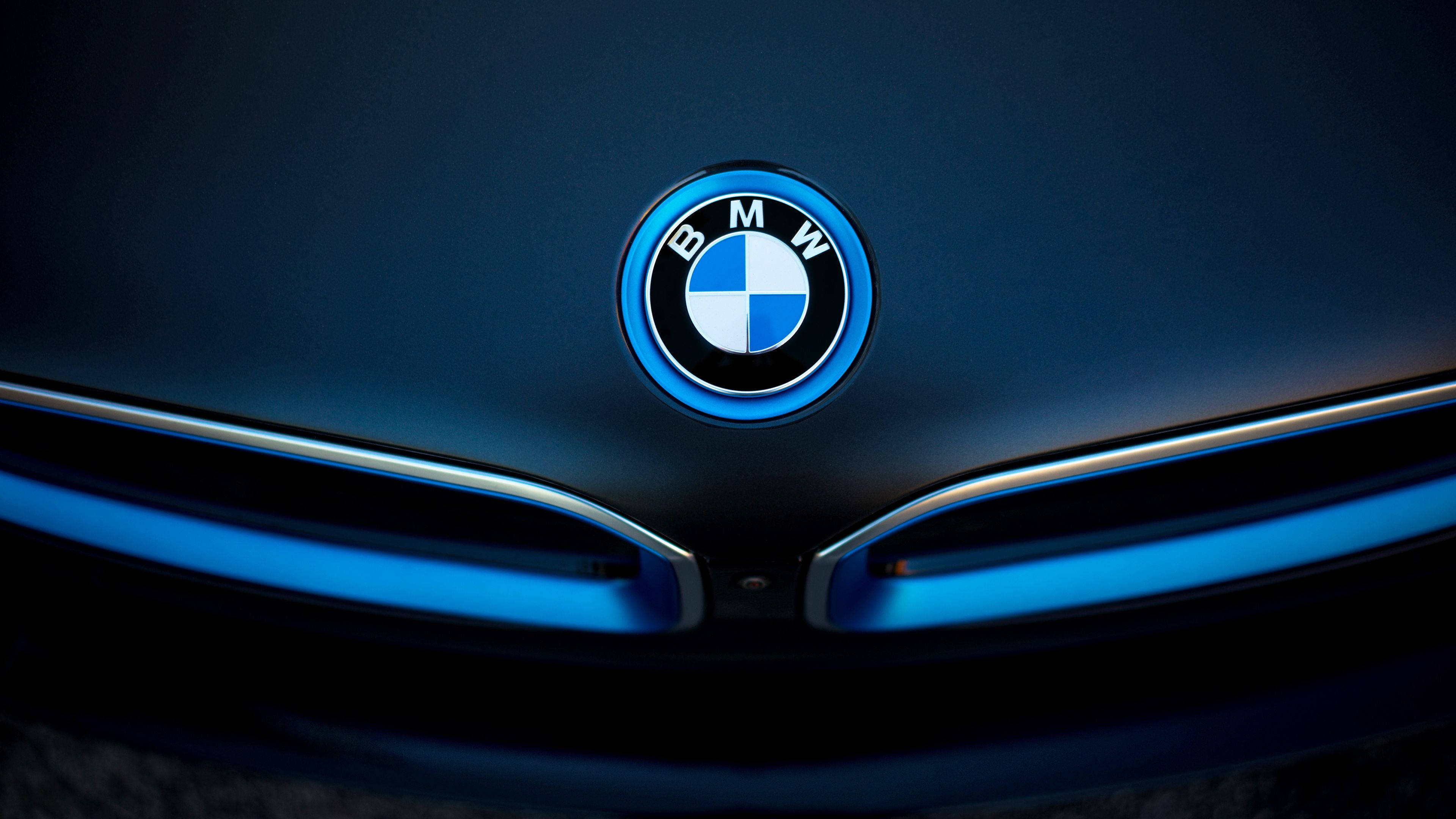 桌布 壁紙 — 特寫BMW標誌在戲劇性燈光下於時尚深色引擎蓋上發出藍光。