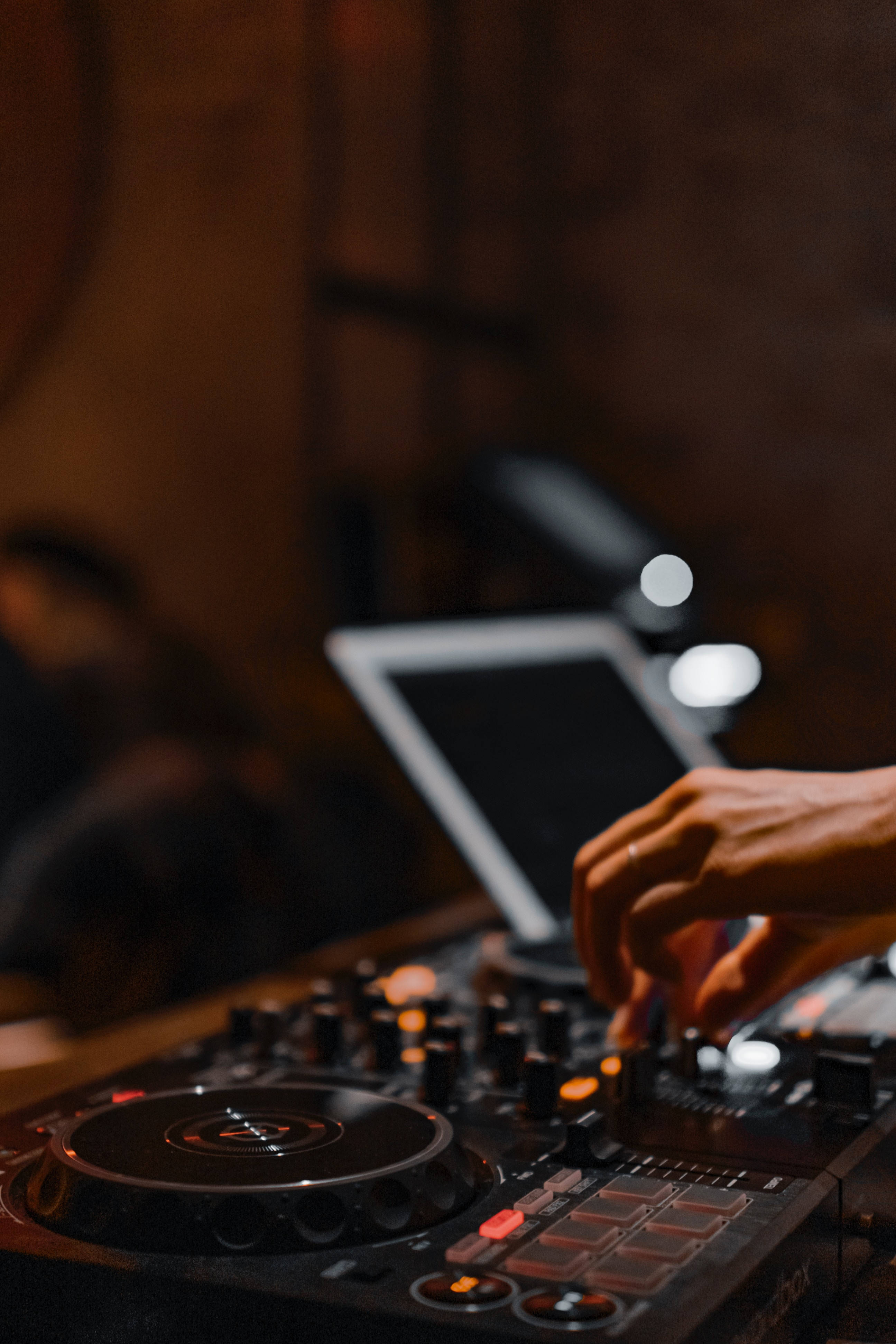 DJ 桌布 壁紙 — 特寫DJ的手在溫暖的環境燈光下調整黑色控制器上的旋鈕。
