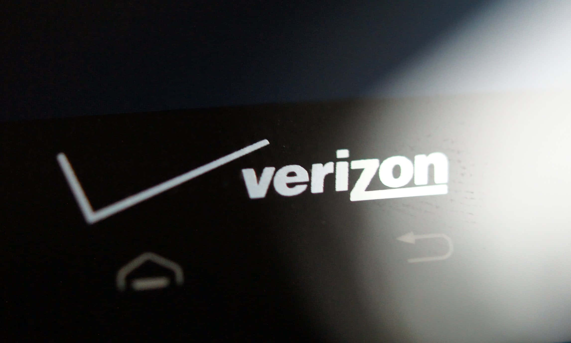 威訊 桌布 壁紙 — 特寫Verizon標誌在黑暗螢幕上發出白色光芒，帶有模糊的導航圖示。