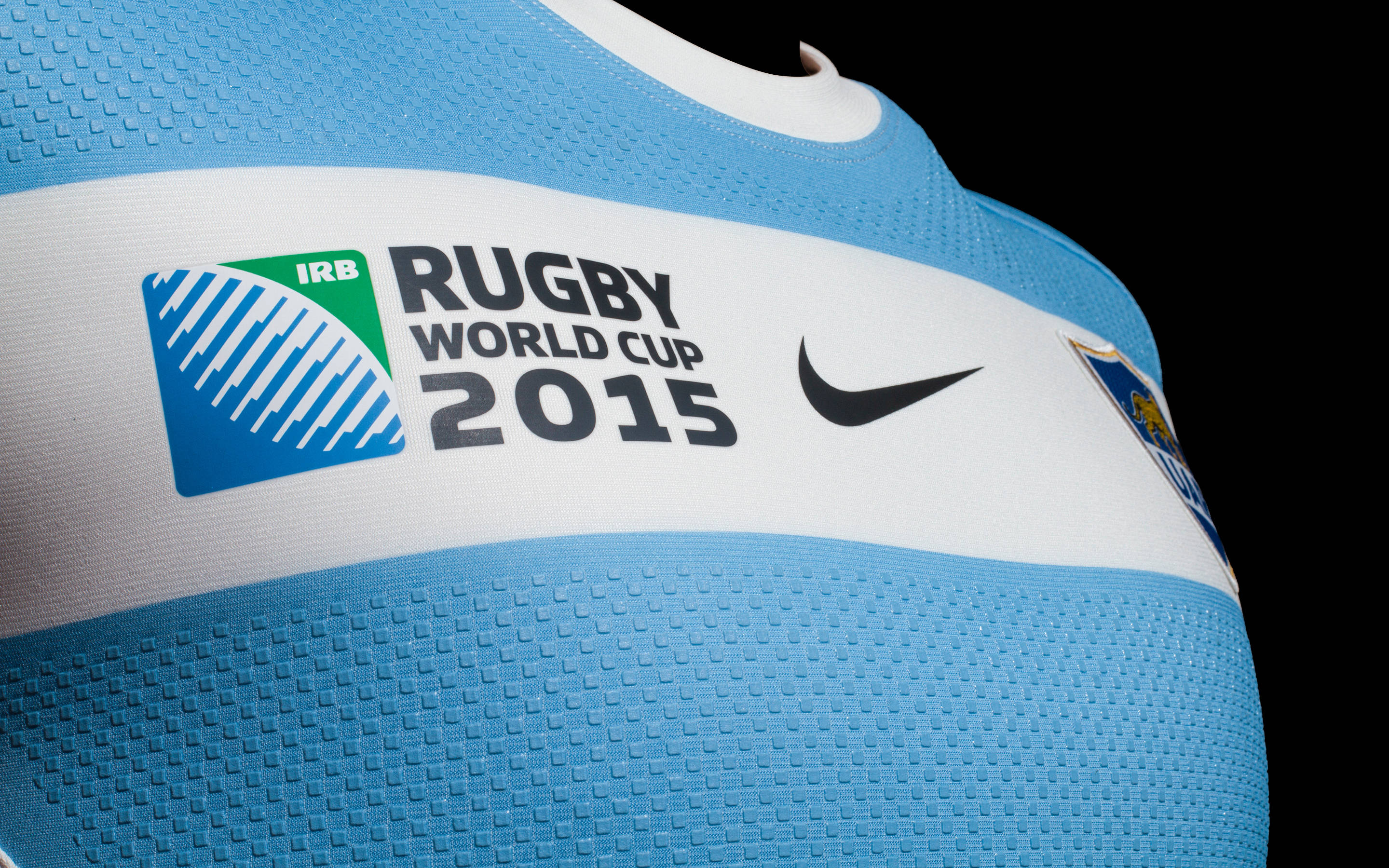 Nike iPhone 桌布 壁紙 — 特寫一件淺藍色橄欖球球衣，上面有IRB Rugby World Cup 2015標誌和Nike swoosh，背景為黑色。