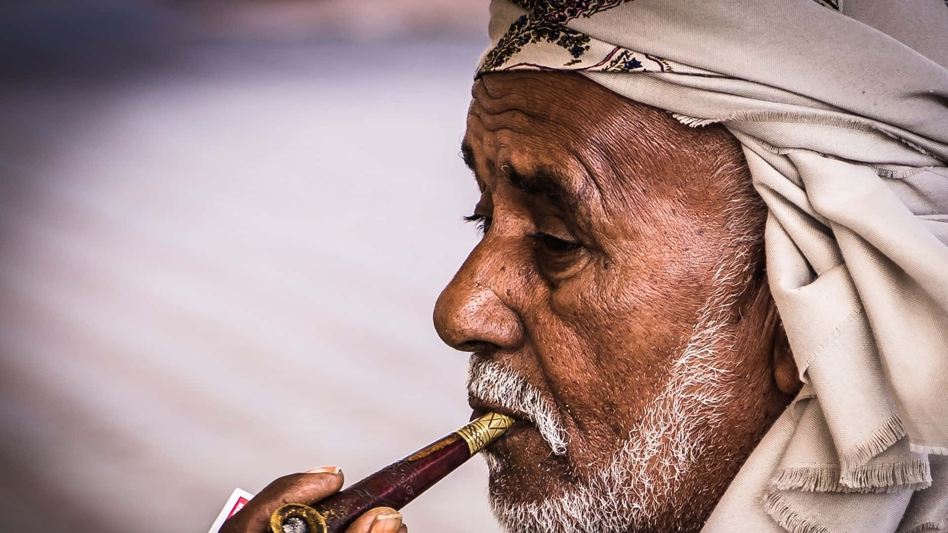 Arab Man 桌布 壁紙 — 特寫一位留白鬍子、戴頭巾的老人，神情專注地抽煙斗。