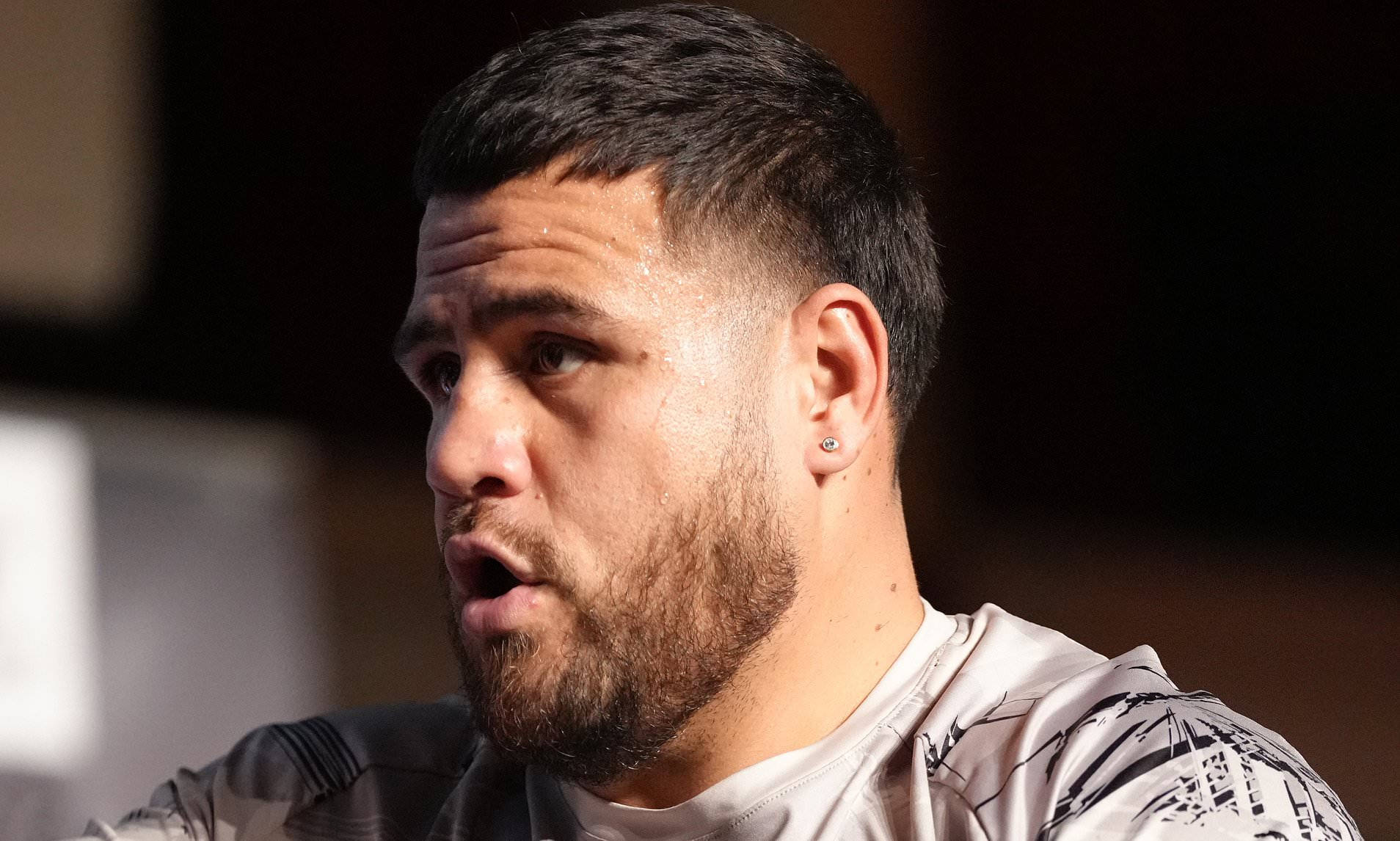 UFC 桌布 壁紙 — 特寫一位留鬍鬚、戴耳環的男子，在昏暗的室內環境中專注地望向鏡頭外。