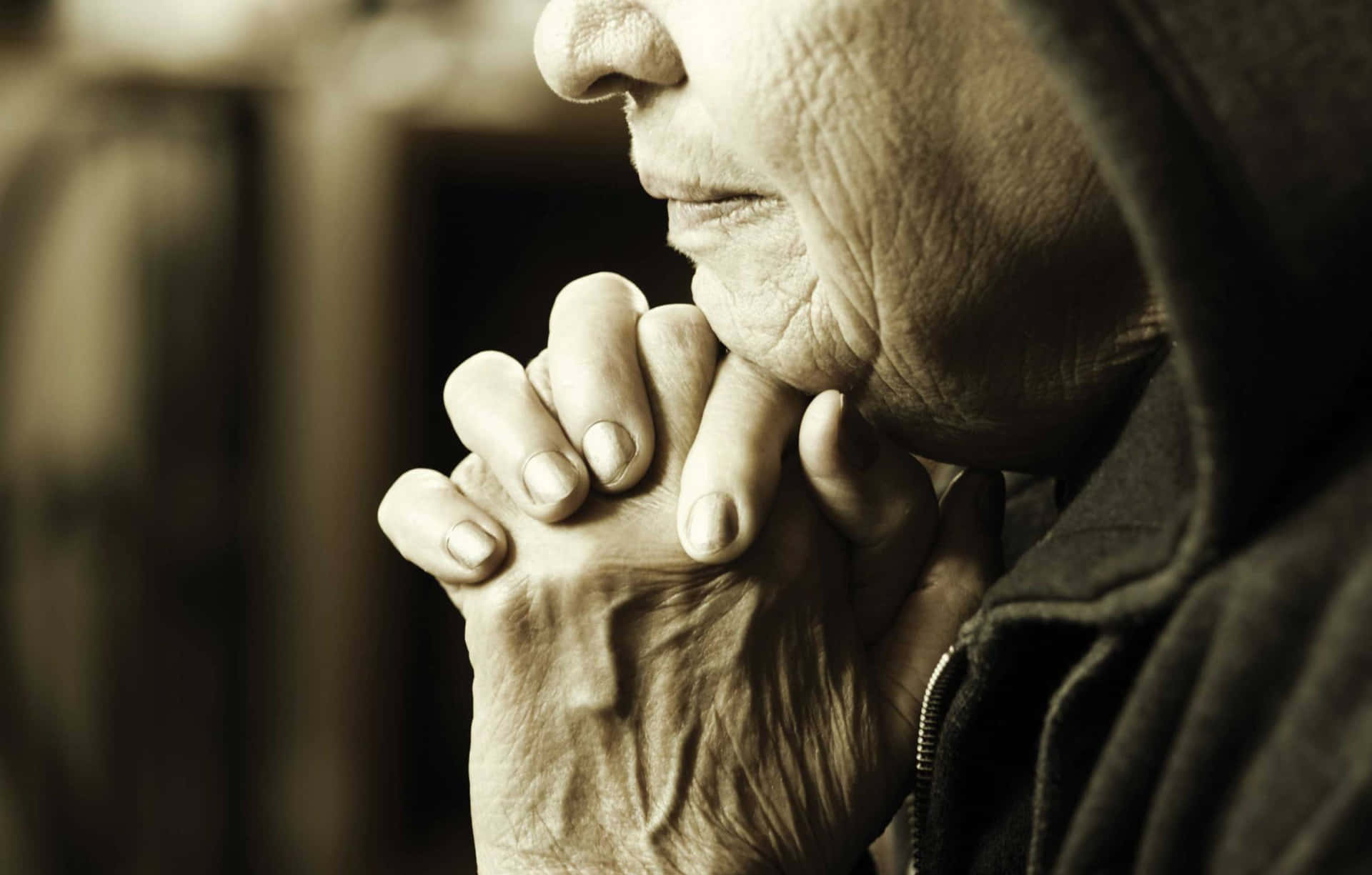 Praying 桌布 壁紙 — 特寫一位長者歷經風霜的雙手合十祈禱，背景是模糊的懷舊色調。