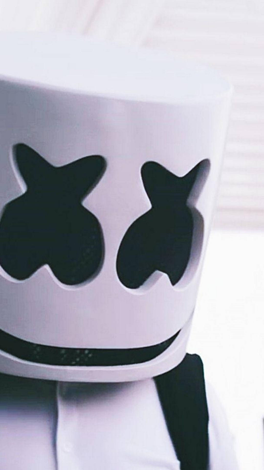 Marshmello 動態圖 桌布 壁紙 — 特寫一個人戴著白色Marshmello頭盔，頭盔上有黑色眼睛和嘴巴鏤空，背景明亮模糊。